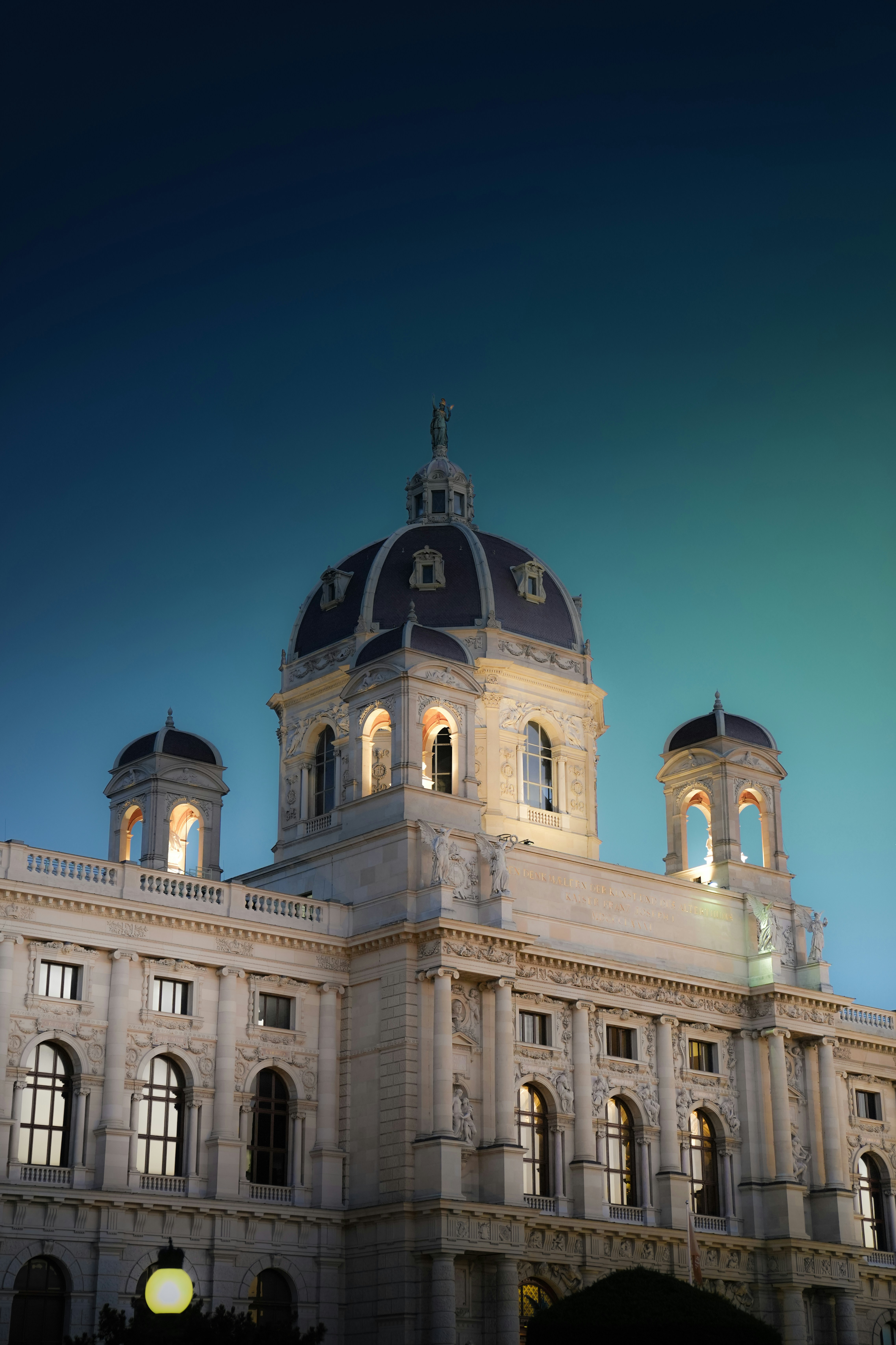 The Kunsthistorisches Museum in Vienna with illuminated domes against a deep blue sky