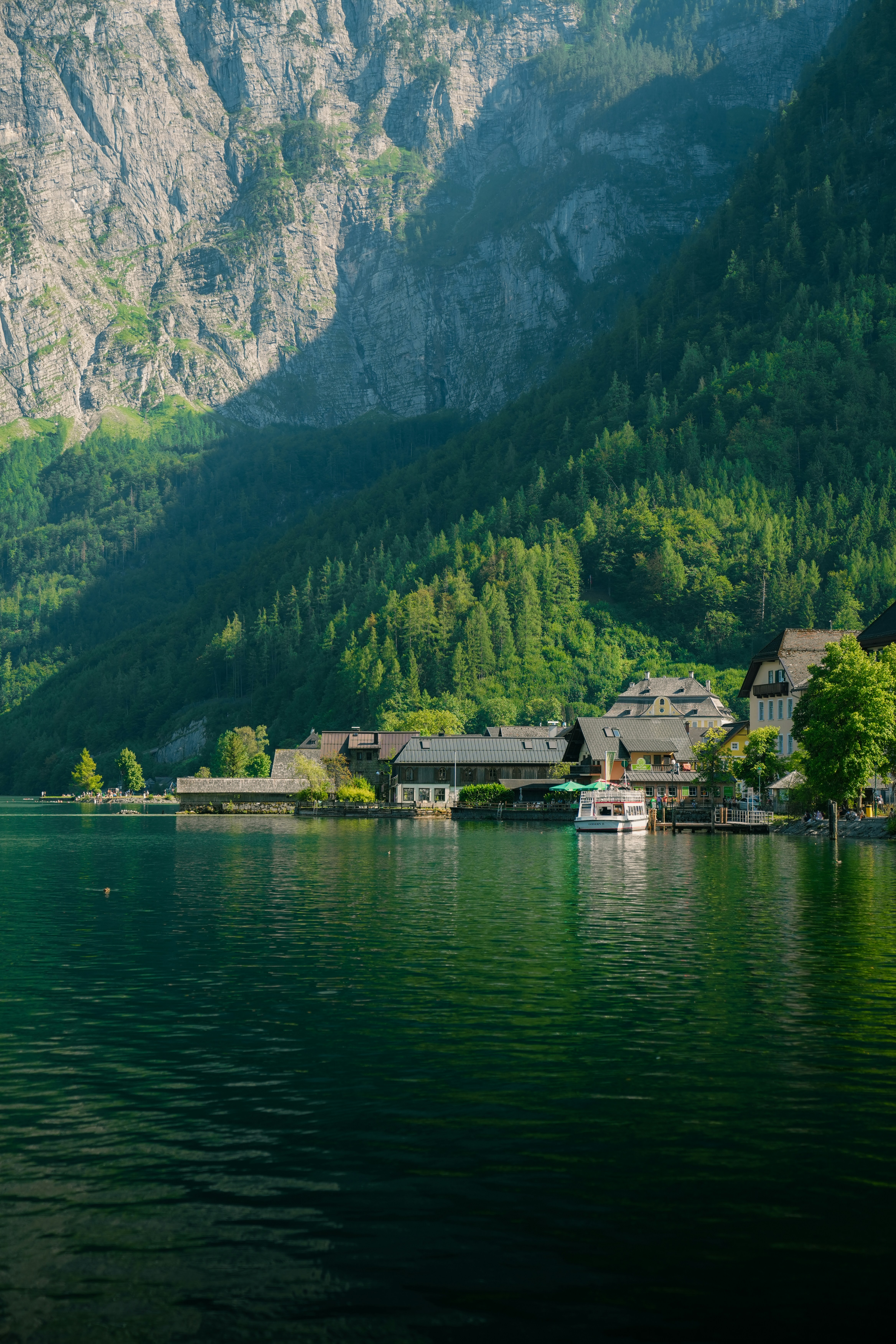 A small village on the shore of a lake beneath steep forested mountains