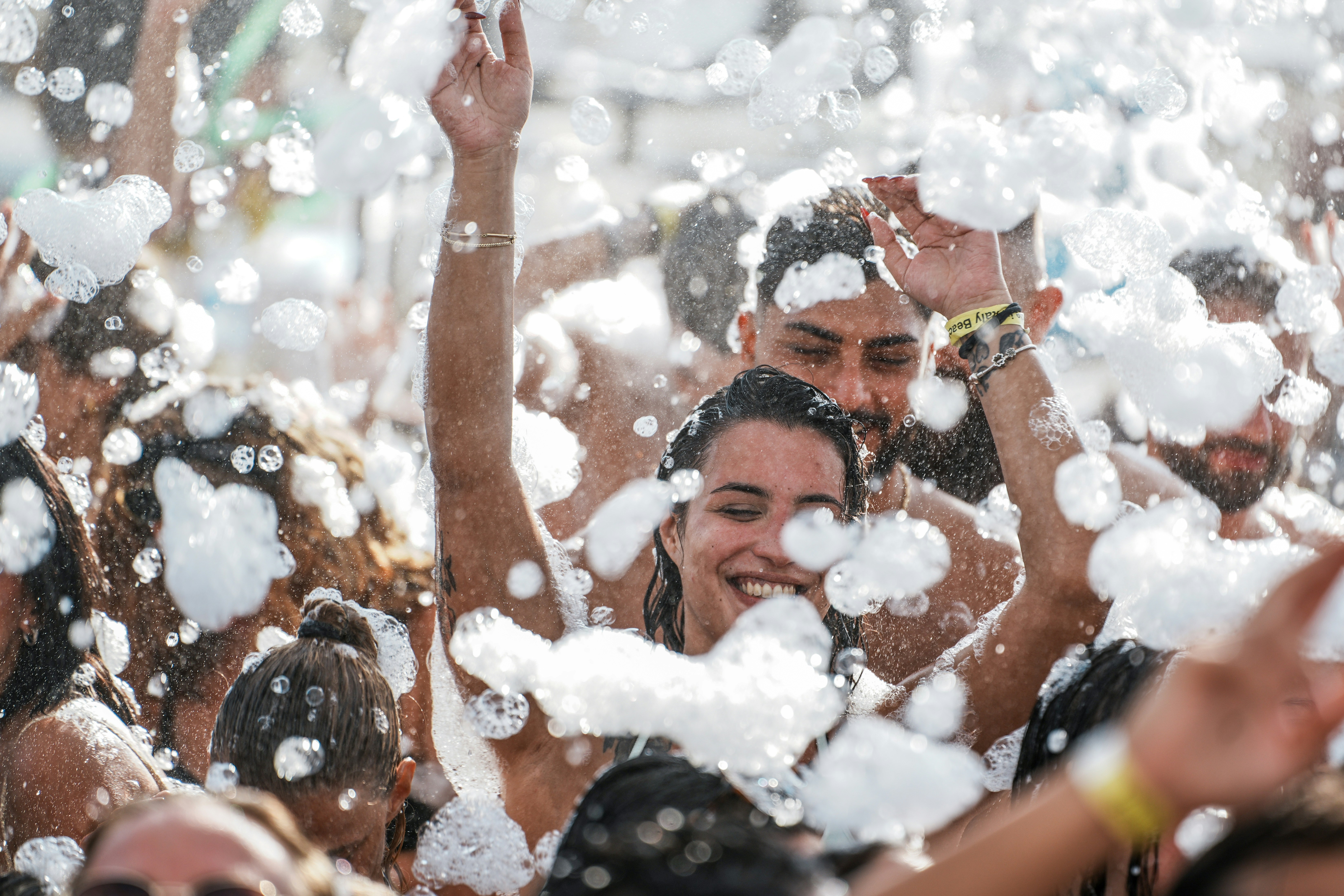 A group of people dancing in a foam party with bubbles in the air