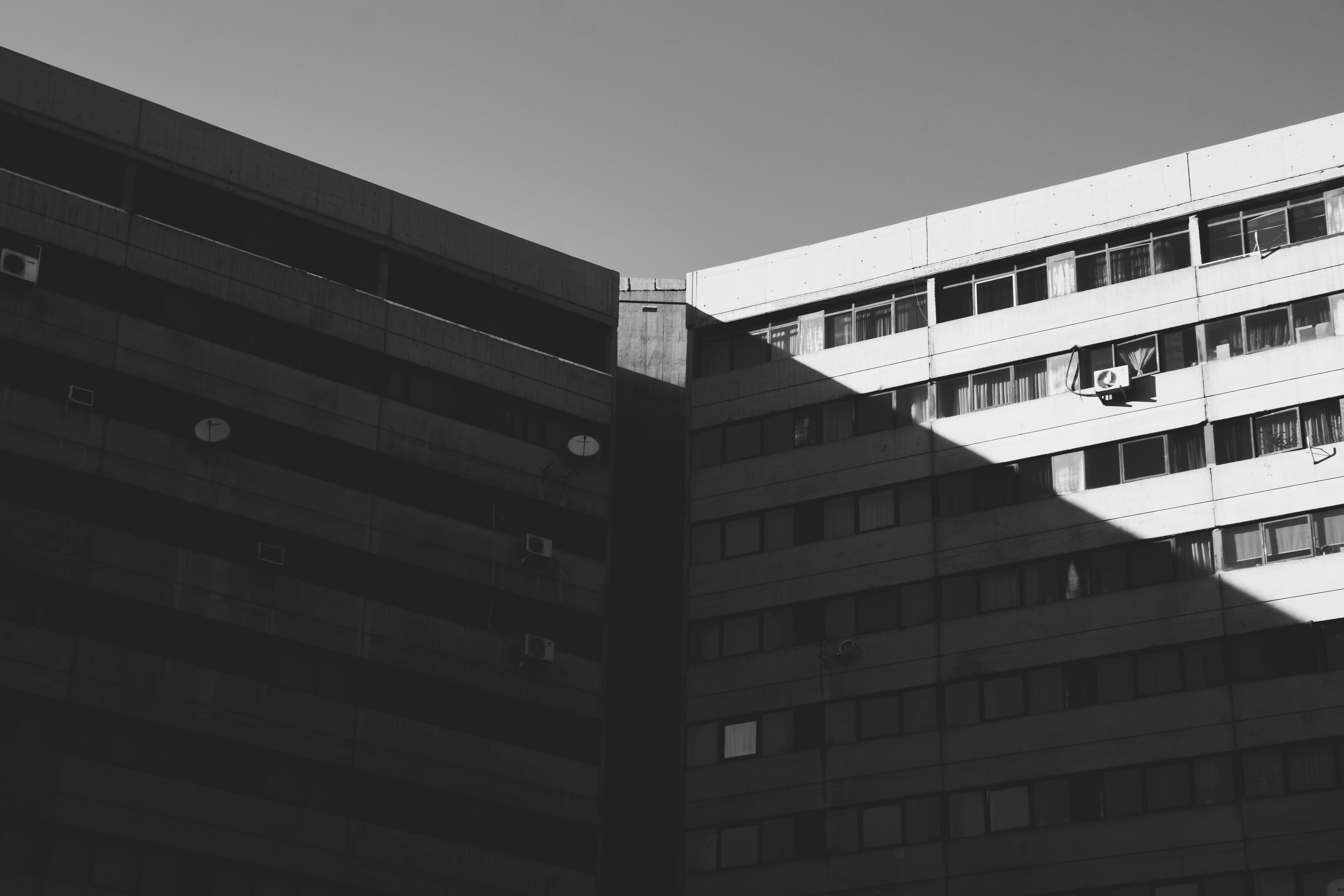Dos edificios de apartamentos de hormigón se encuentran en ángulo con sombras nítidas en blanco y negro