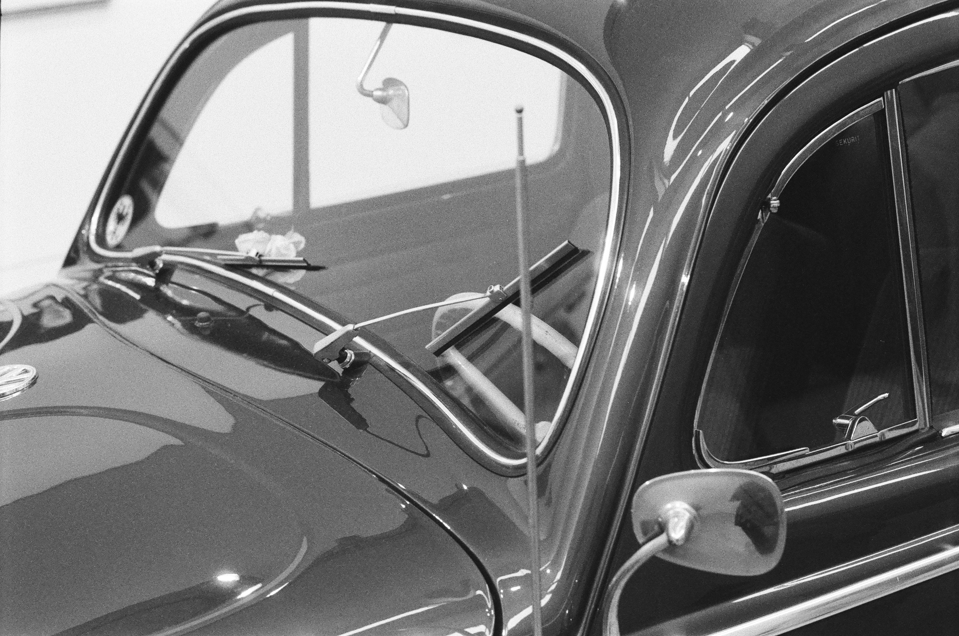 The windshield and hood of a vintage Volkswagen Beetle in black and white