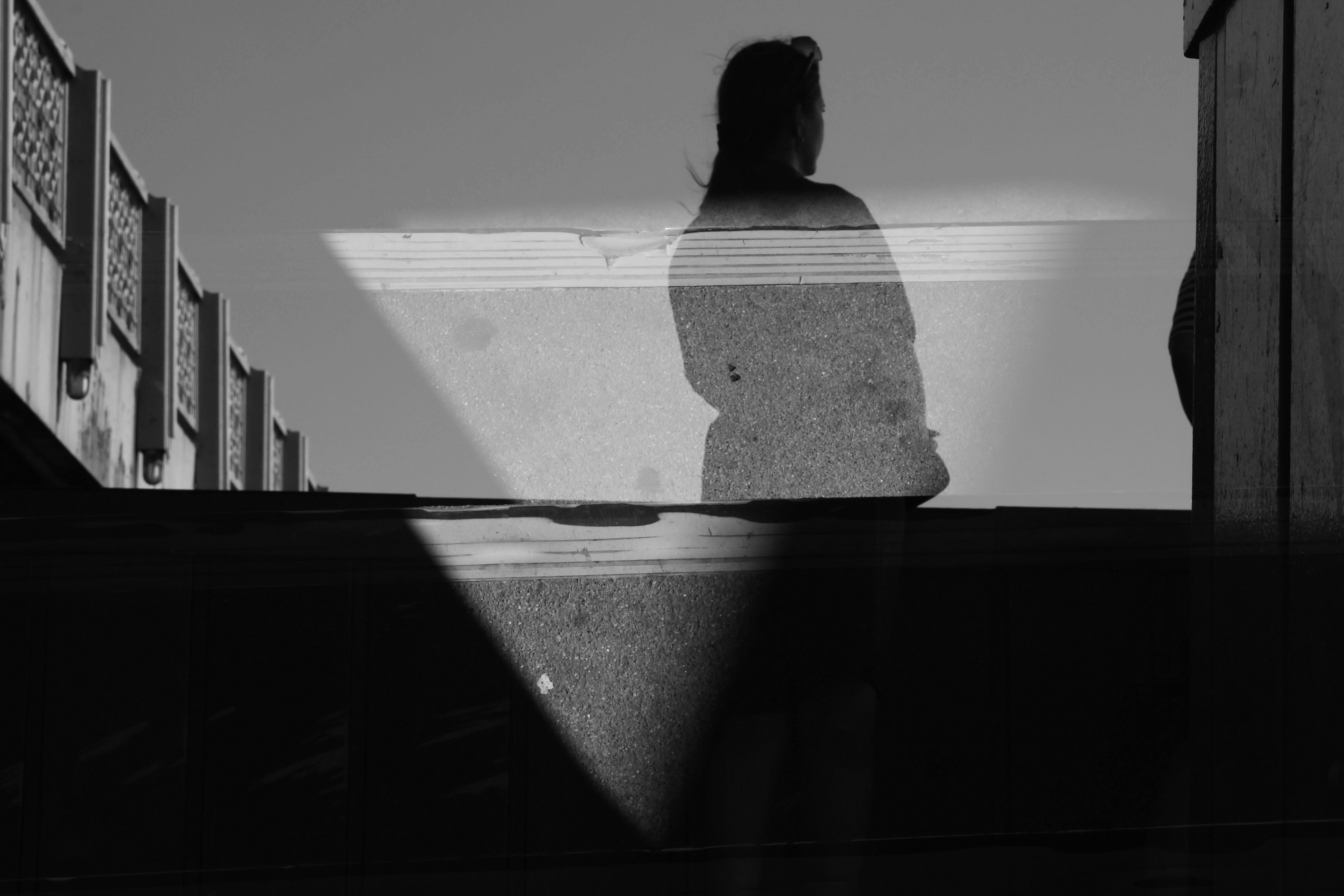 A double exposure silhouette of a person against a textured wall and building
