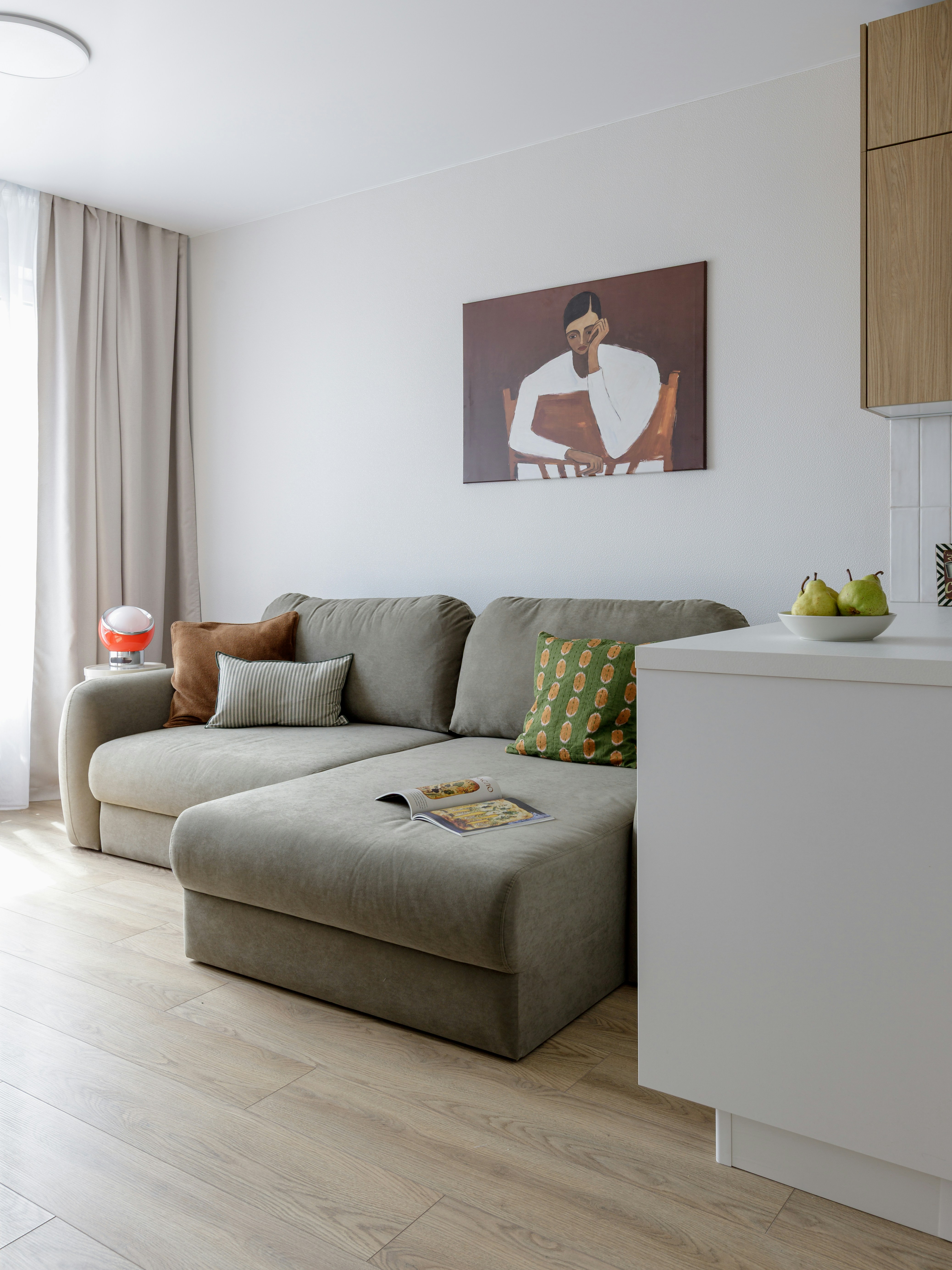 A grey sectional sofa with patterned pillows and a magazine in a living room