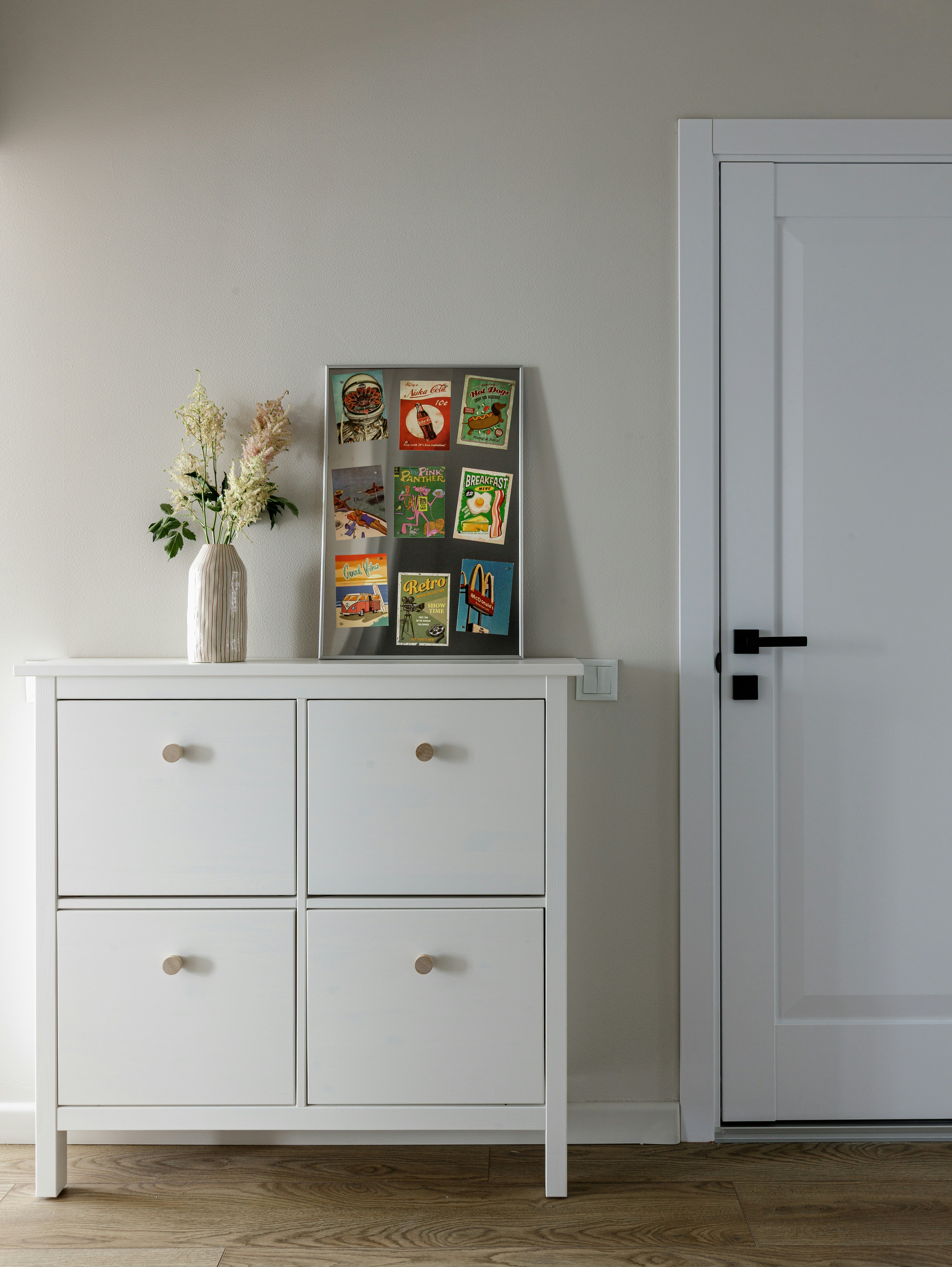 A white cabinet with a vase of flowers and a magnetic board with stickers