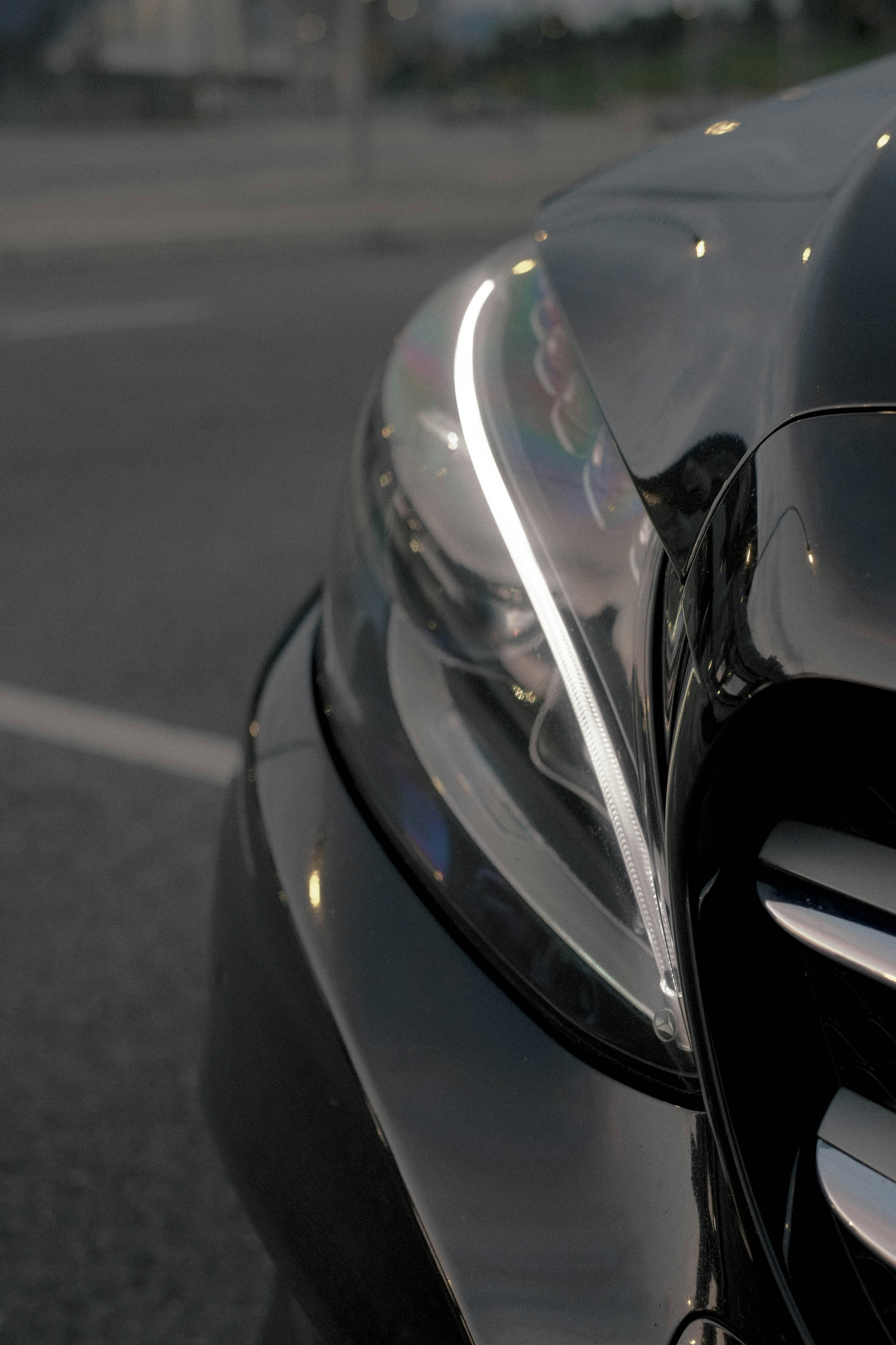 A close-up of a black car headlight with a glowing white LED strip