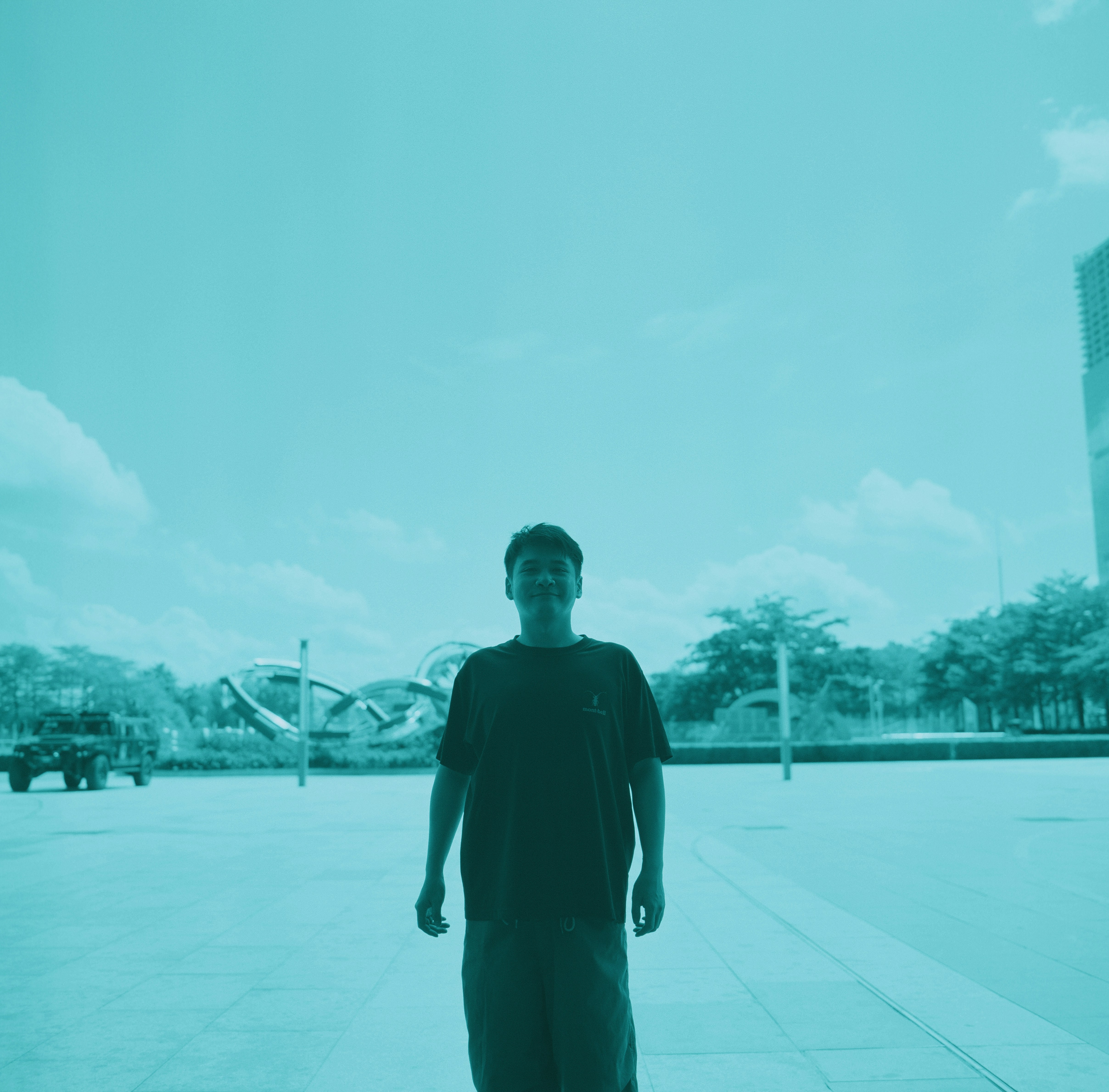 A person in a dark t-shirt on a paved plaza under a blue sky