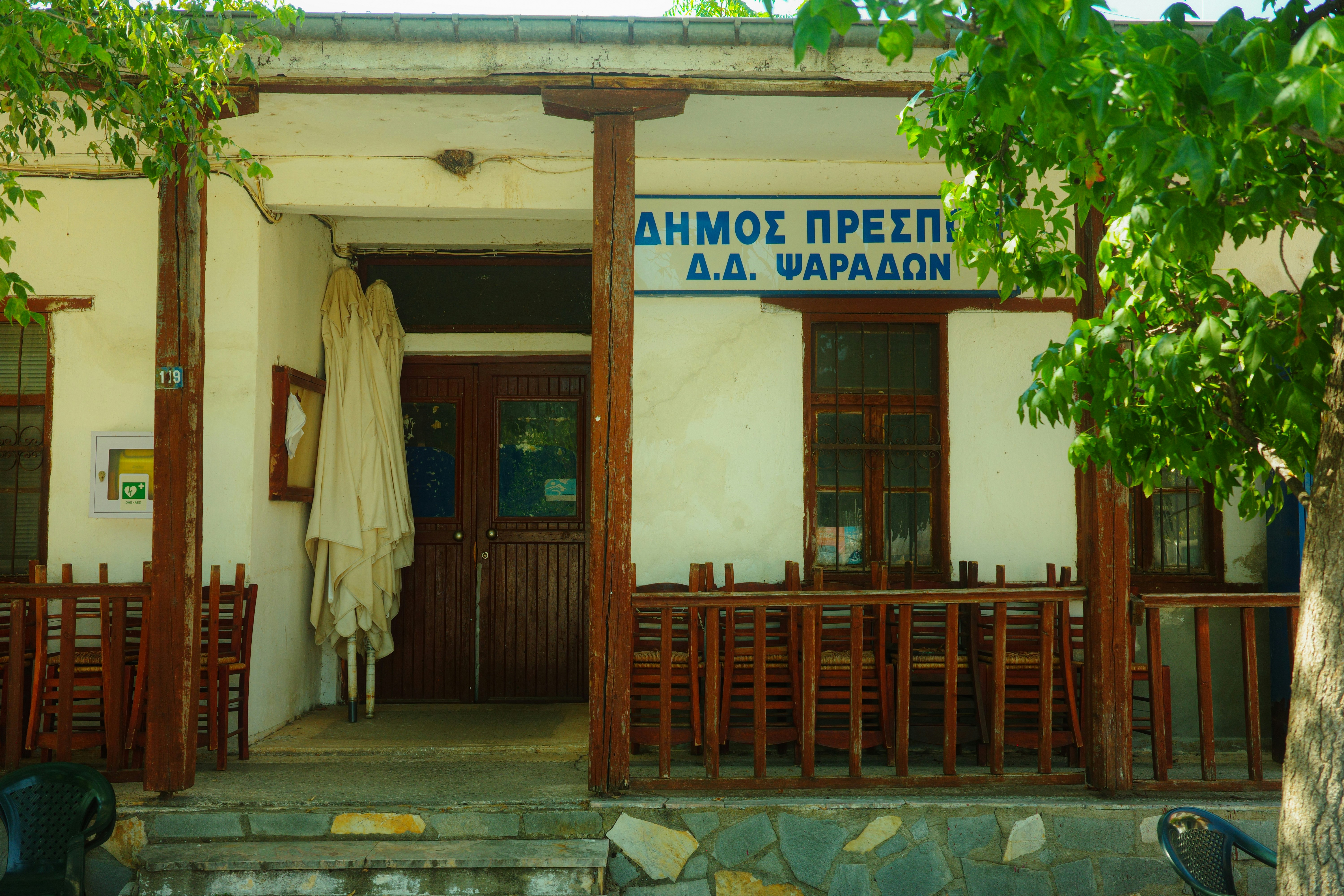 A building with a wooden porch and chairs in Psarades, Greece