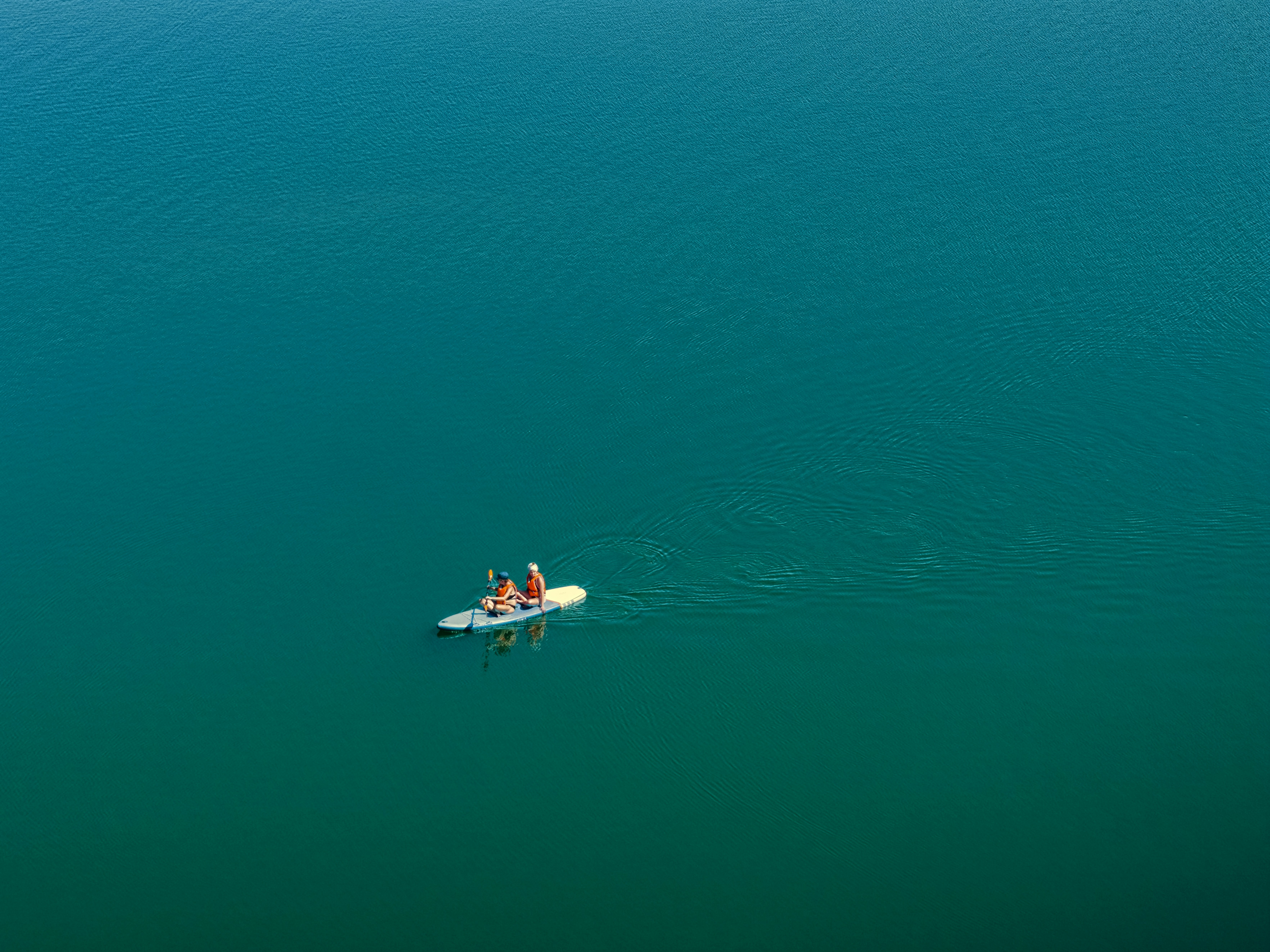 Two people on a paddleboard in the middle of deep blue water