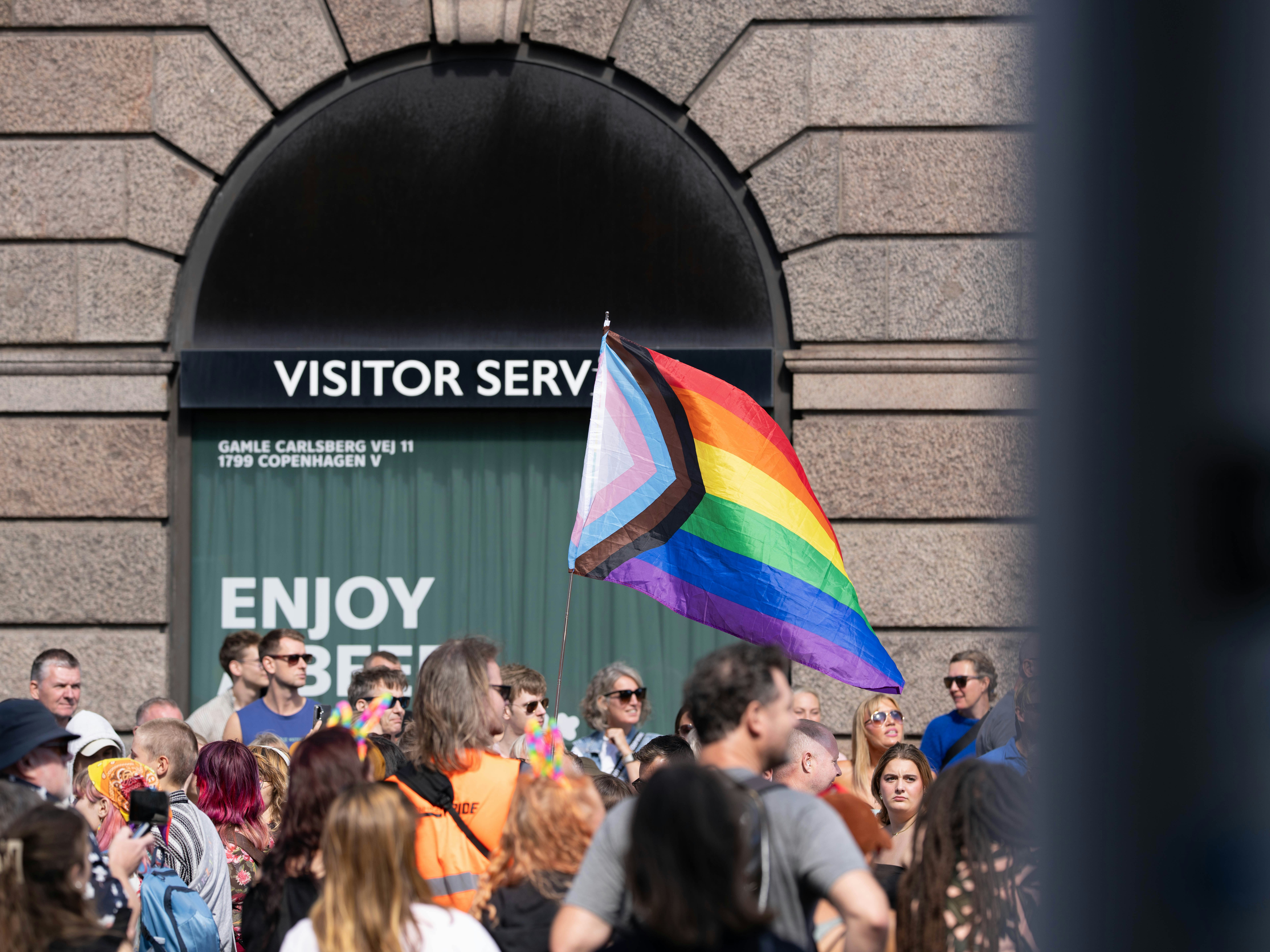 Un drapeau de la fierté du progrès flottant au-dessus d’une foule à Copenhague