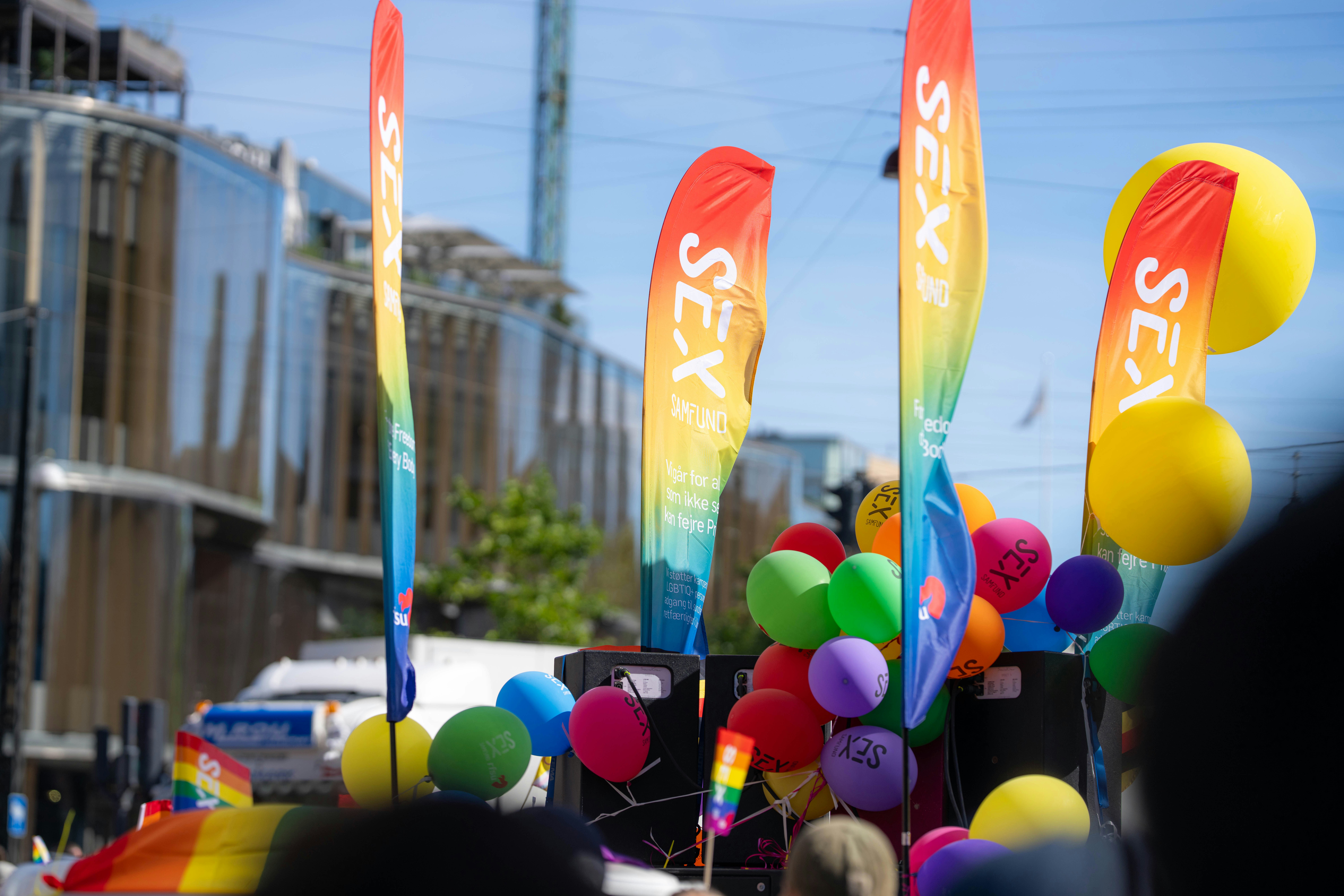 Des drapeaux et des ballons colorés lors d’un défilé de fierté dans une rue de la ville