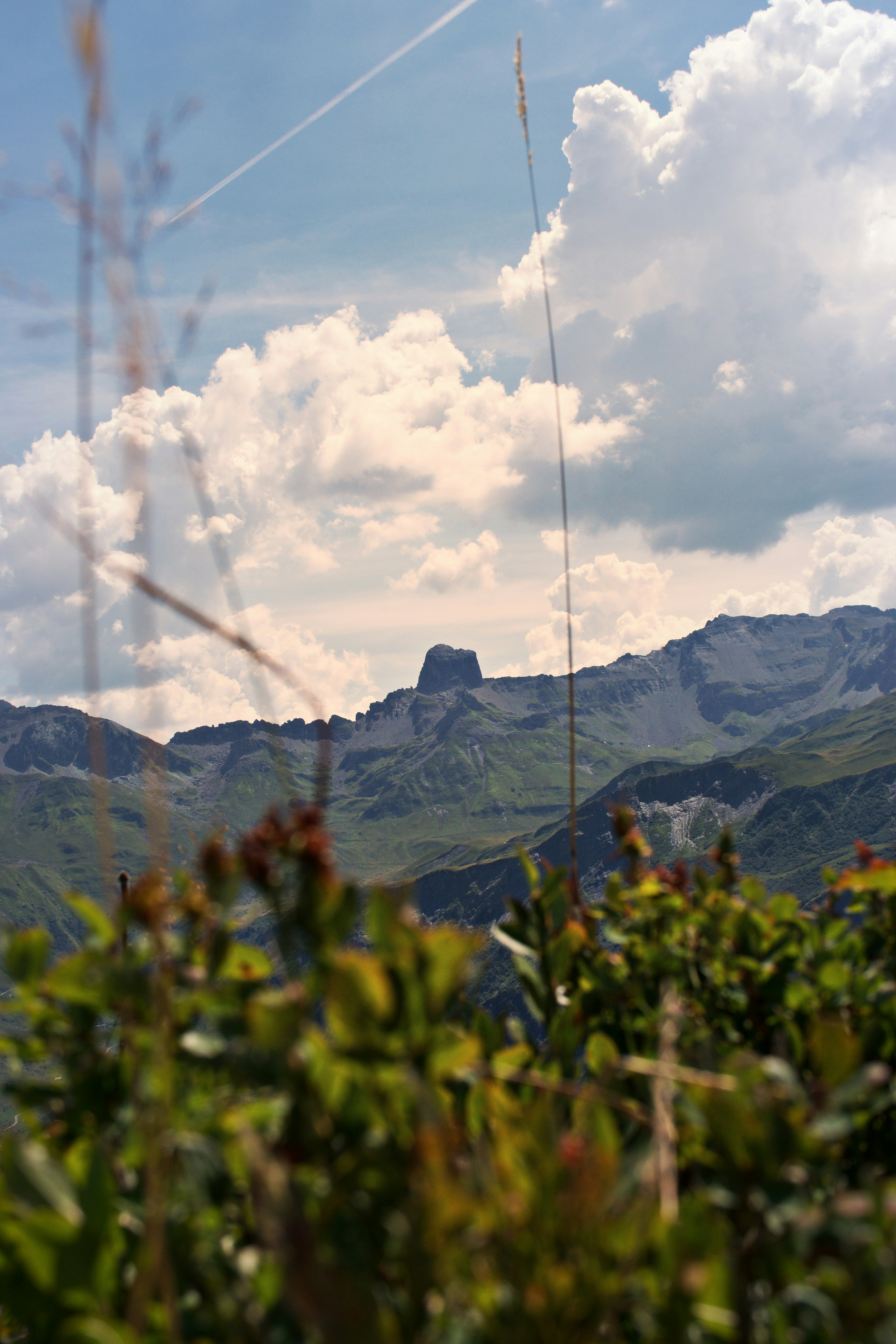 Green mountain slopes under a blue sky with large white clouds