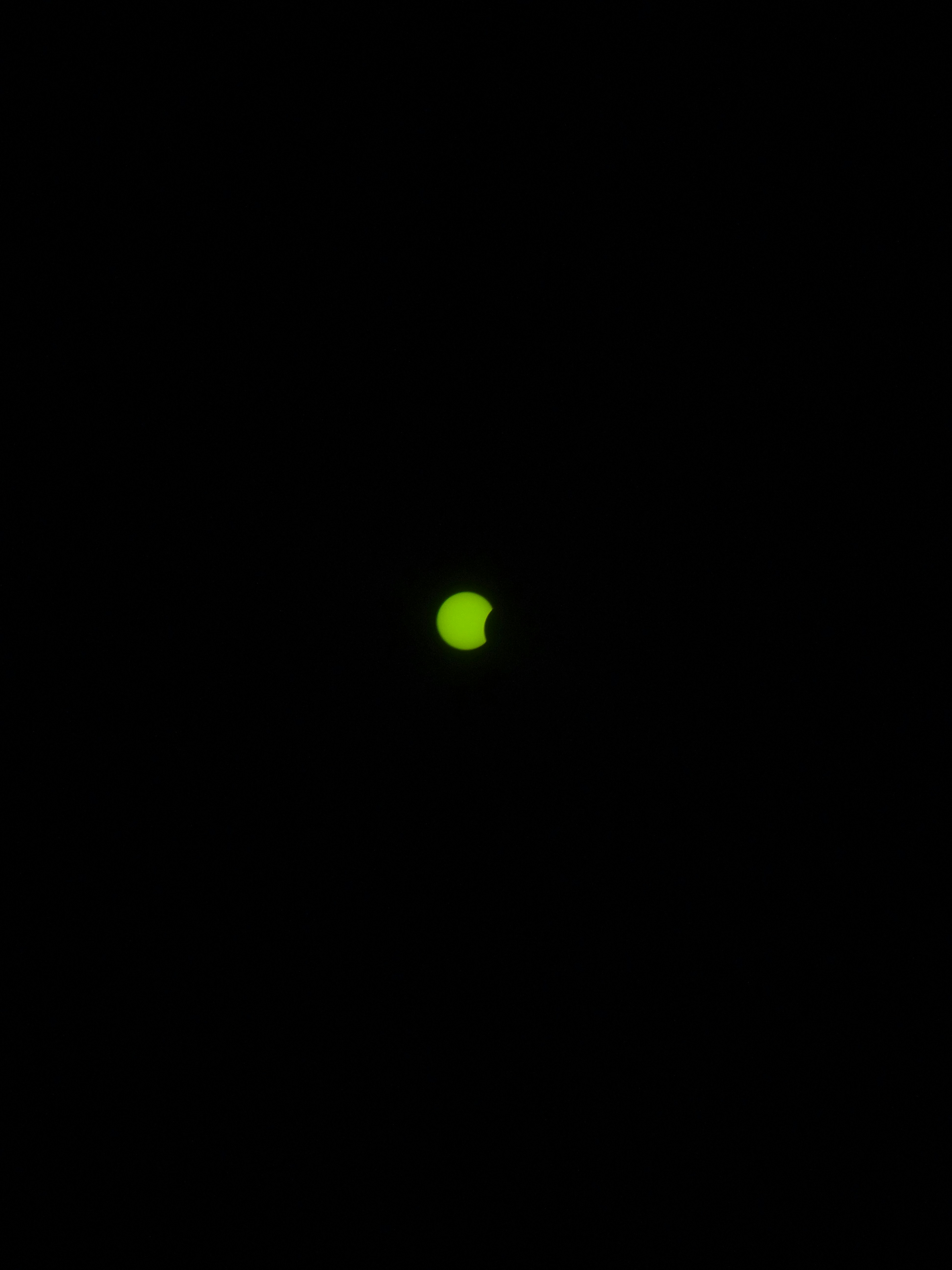 A partial solar eclipse showing a bright crescent sun against a black sky