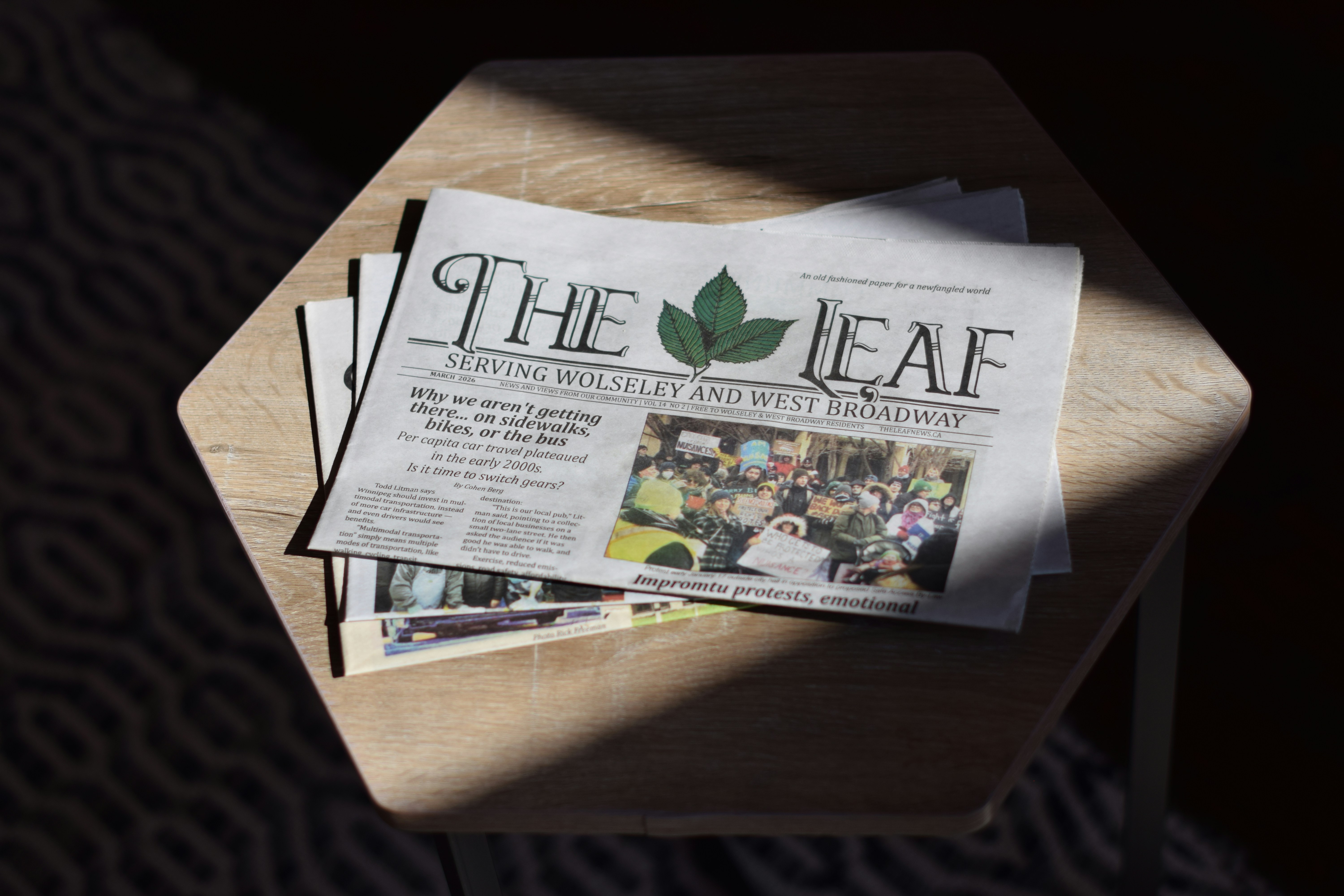 A copy of The Leaf newspaper on a wooden table in bright sunlight