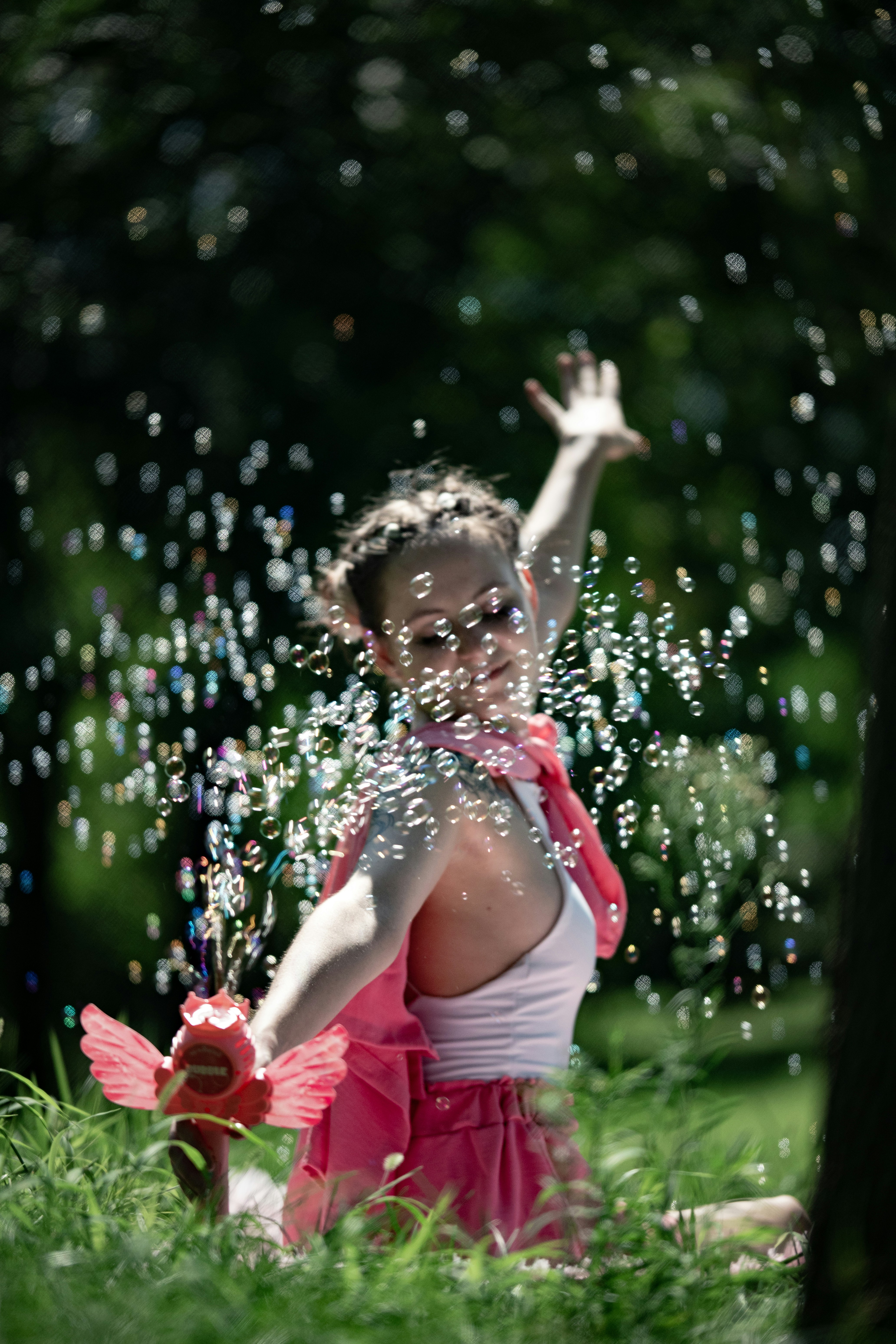 Une femme en tenue rose qui souffle des bulles avec un jouet dans un parc