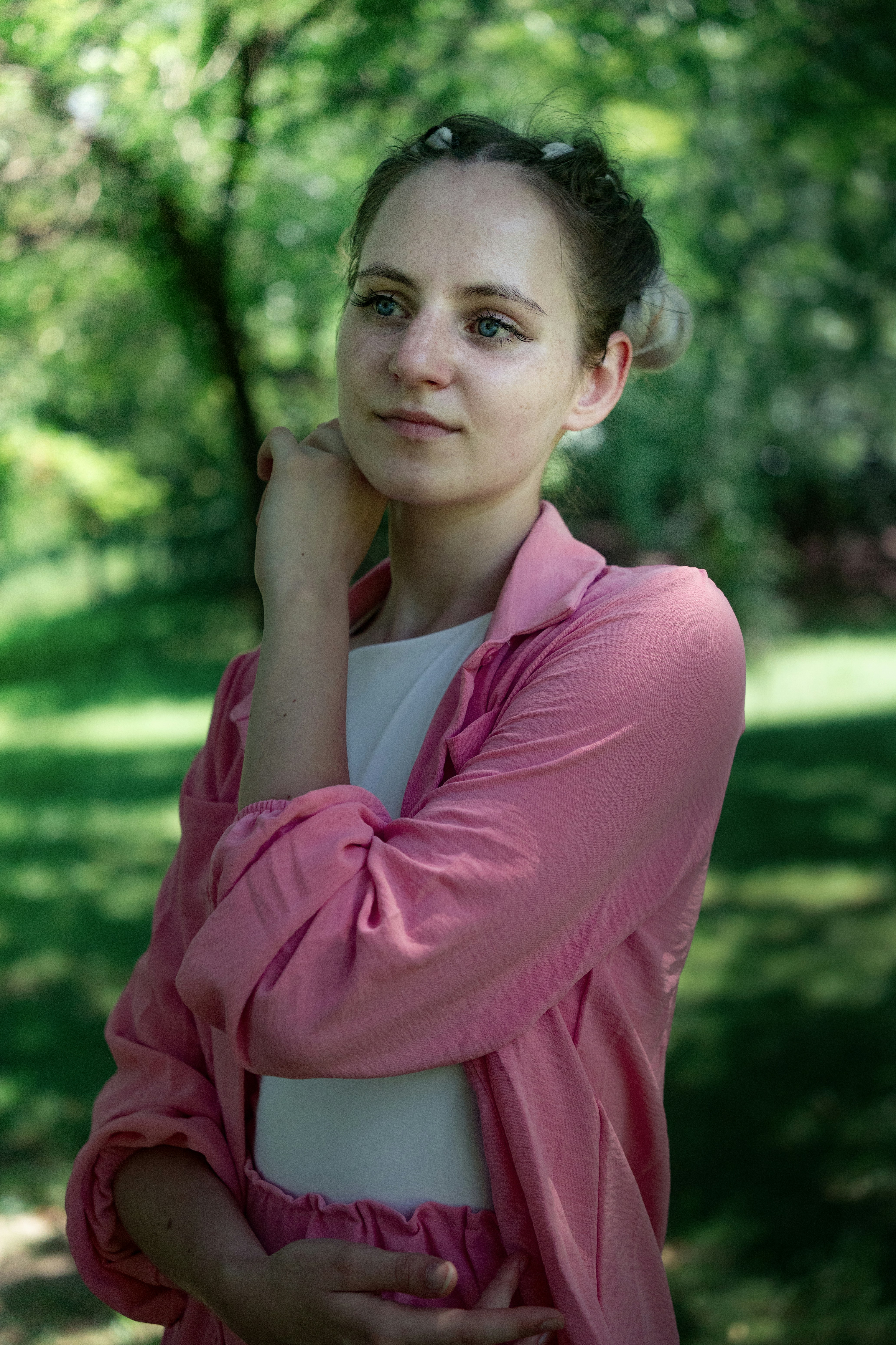 Une femme en chemise rose et haut blanc dans un parc baigné de soleil