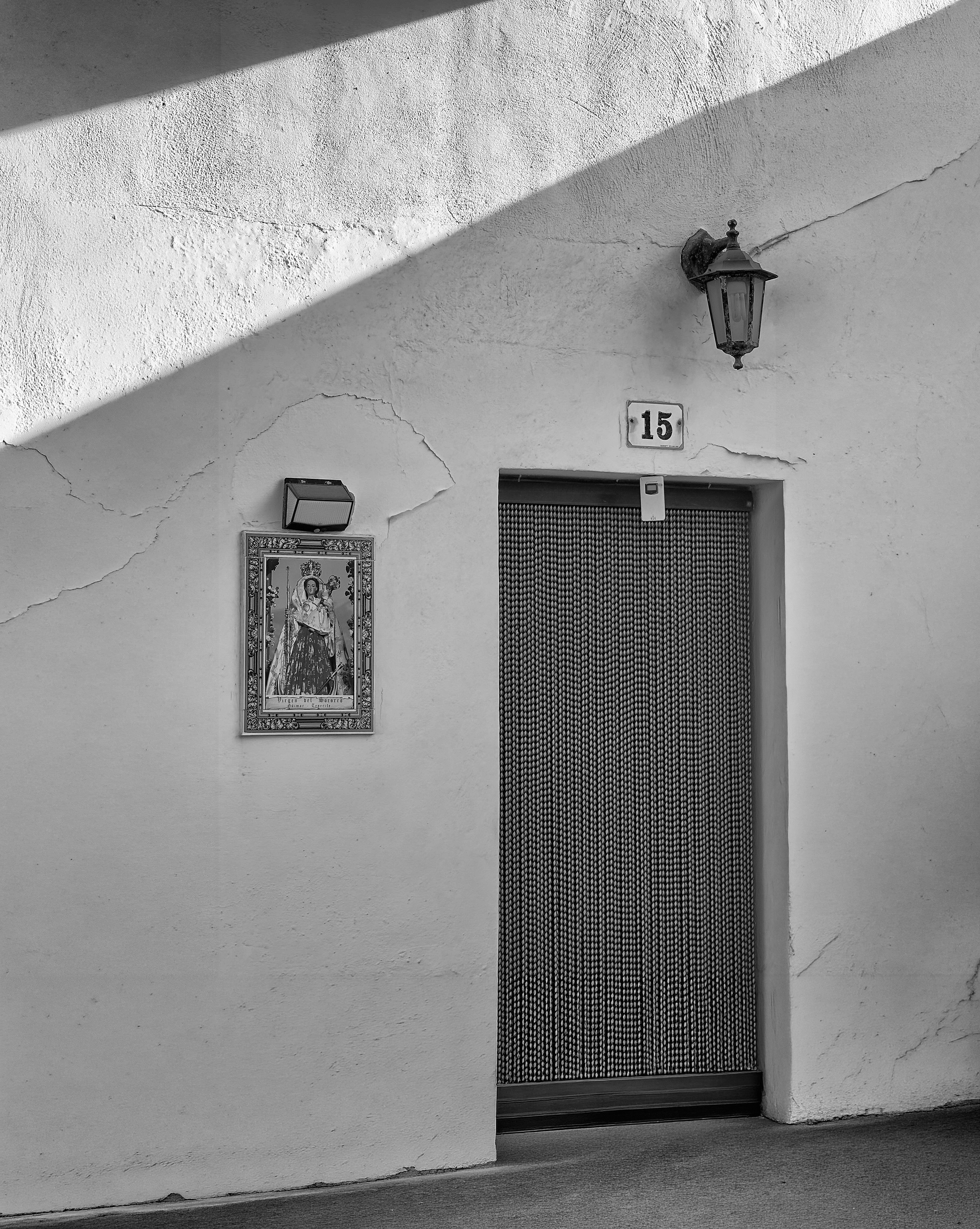 Une porte avec un rideau perlé, une lampe murale et un carrelage religieux