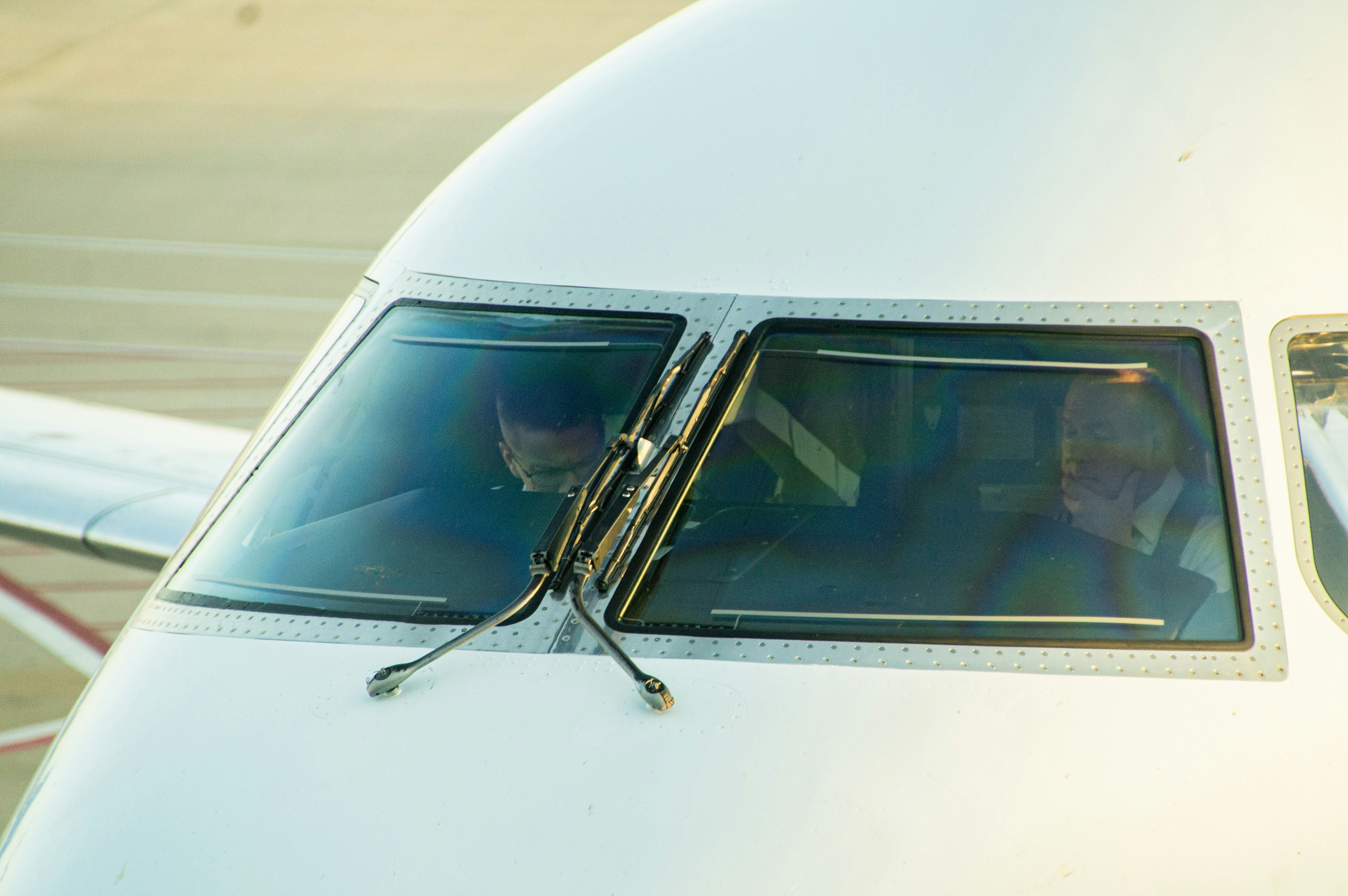 Two pilots in the cockpit of a white airplane under warm light