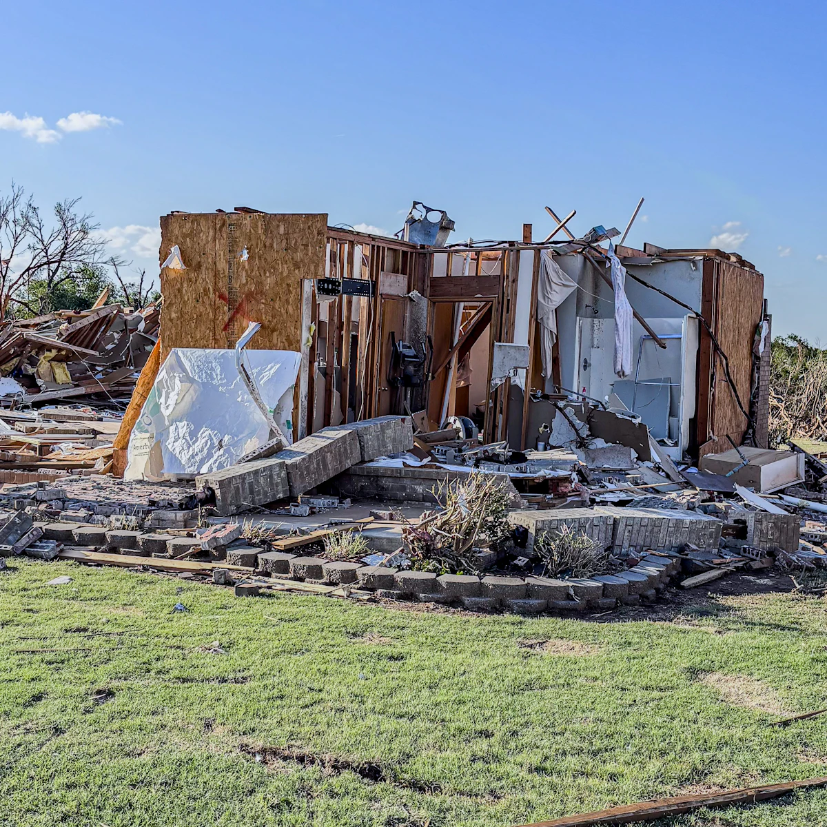 A house reduced to its wooden frame and debris after a severe storm
