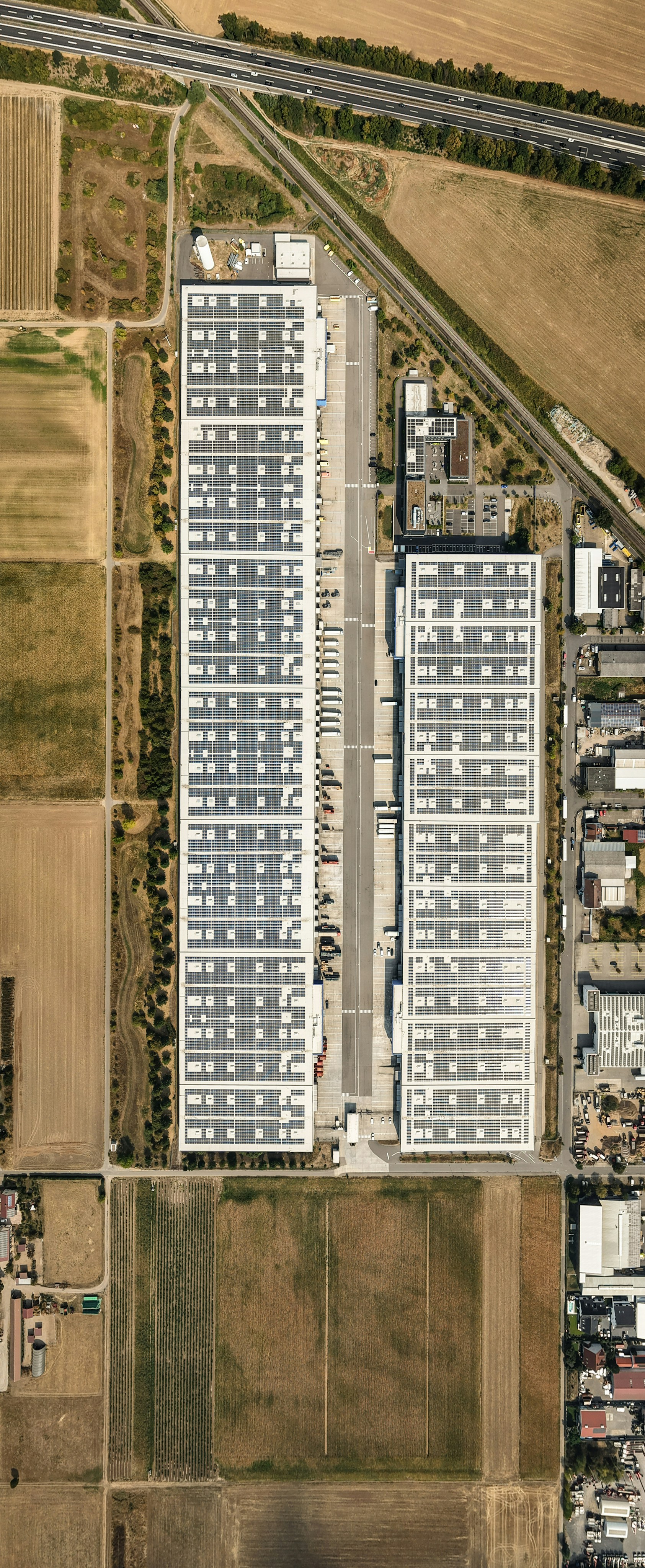 Aerial view of two large industrial warehouses with solar panels on the roofs