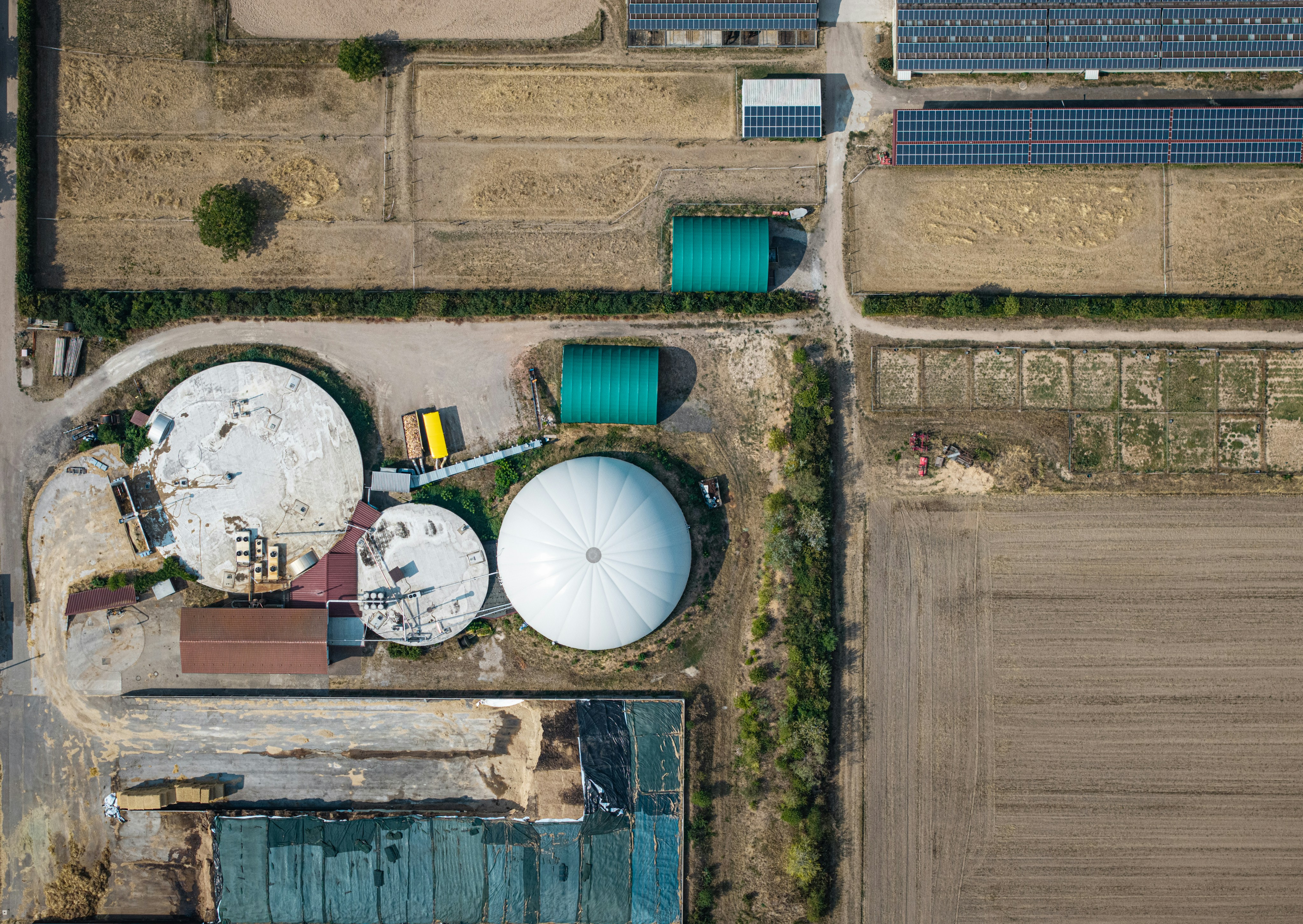 Aerial view of a biogas plant with circular tanks and fields