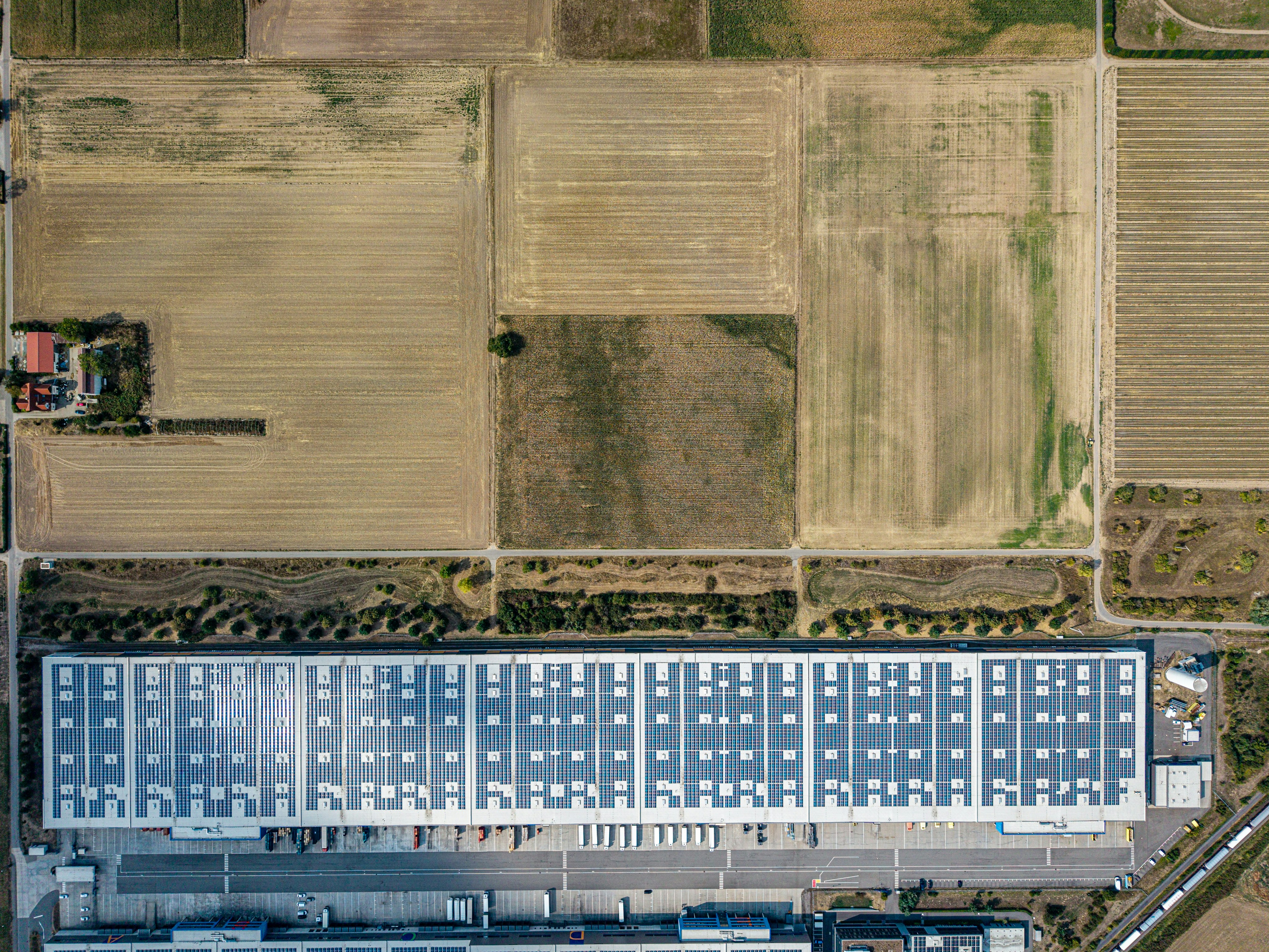 An aerial view of a large warehouse with solar panels on the roof