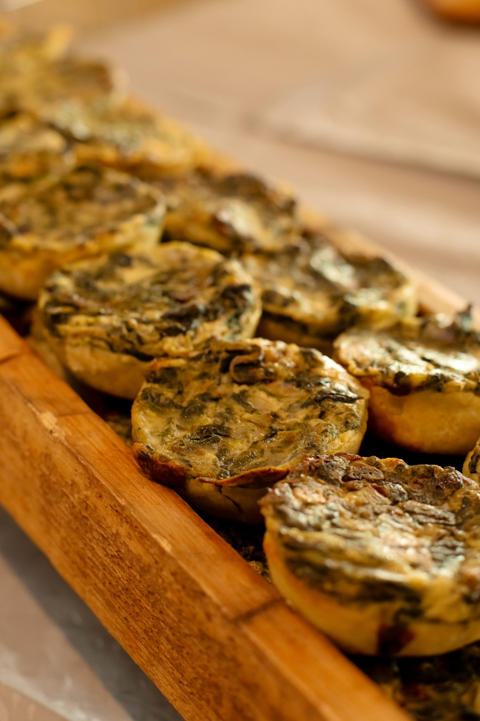 Small baked spinach egg cups lined up on a wooden serving tray