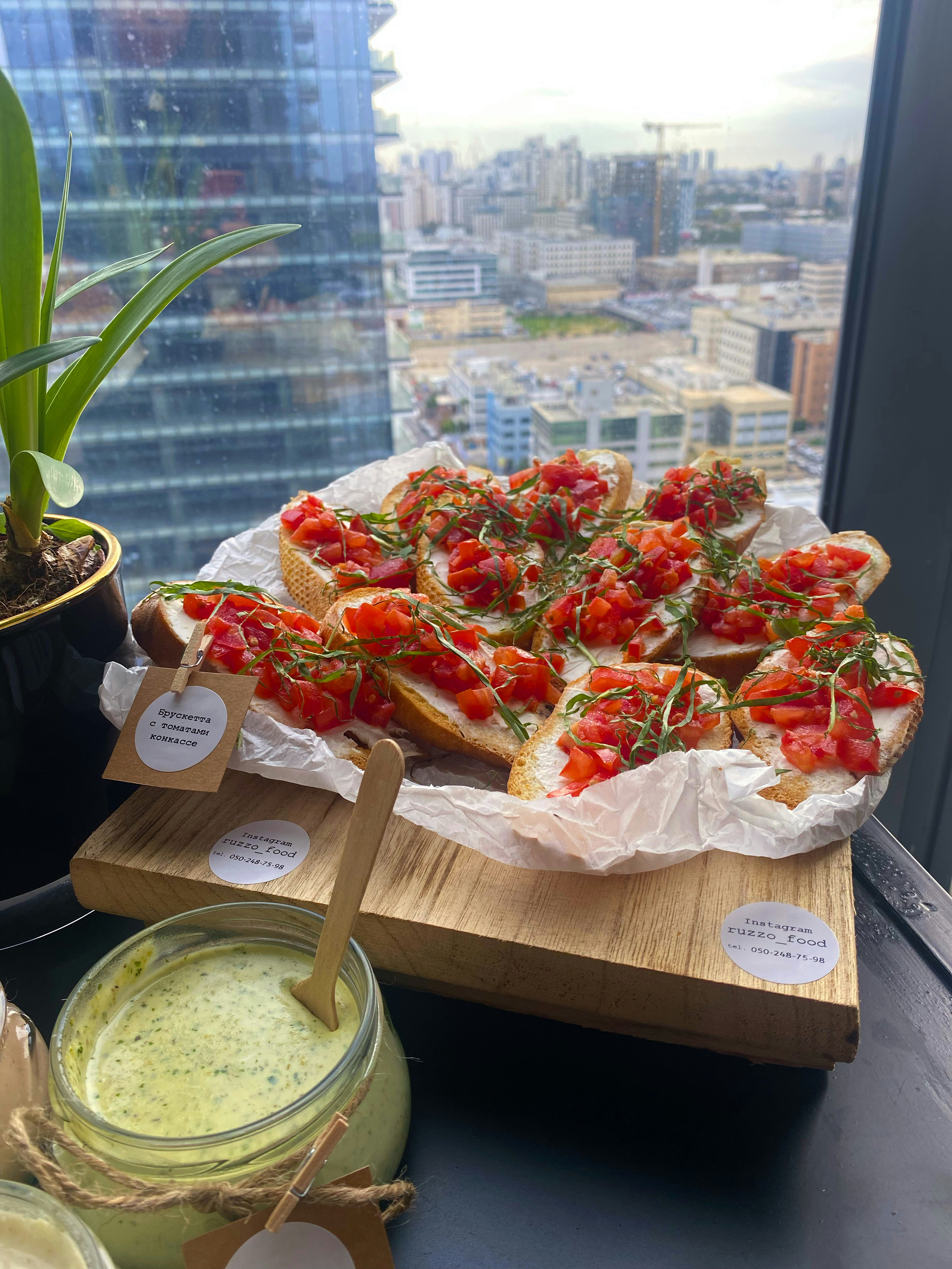 Bruschetta with tomato concasse on a wooden board with a jar of green sauce