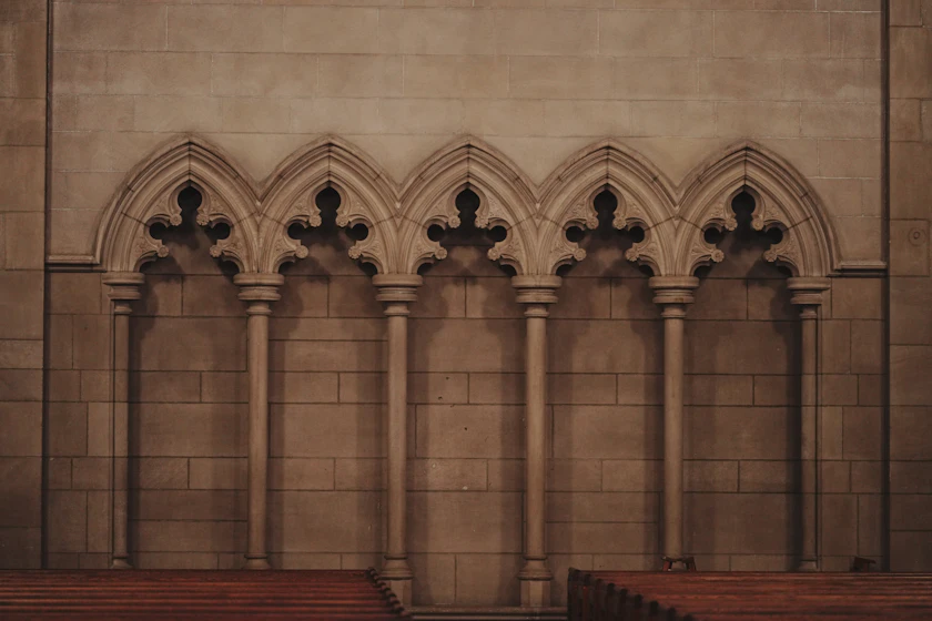 A row of five pointed stone arches on slender columns against a plain wall