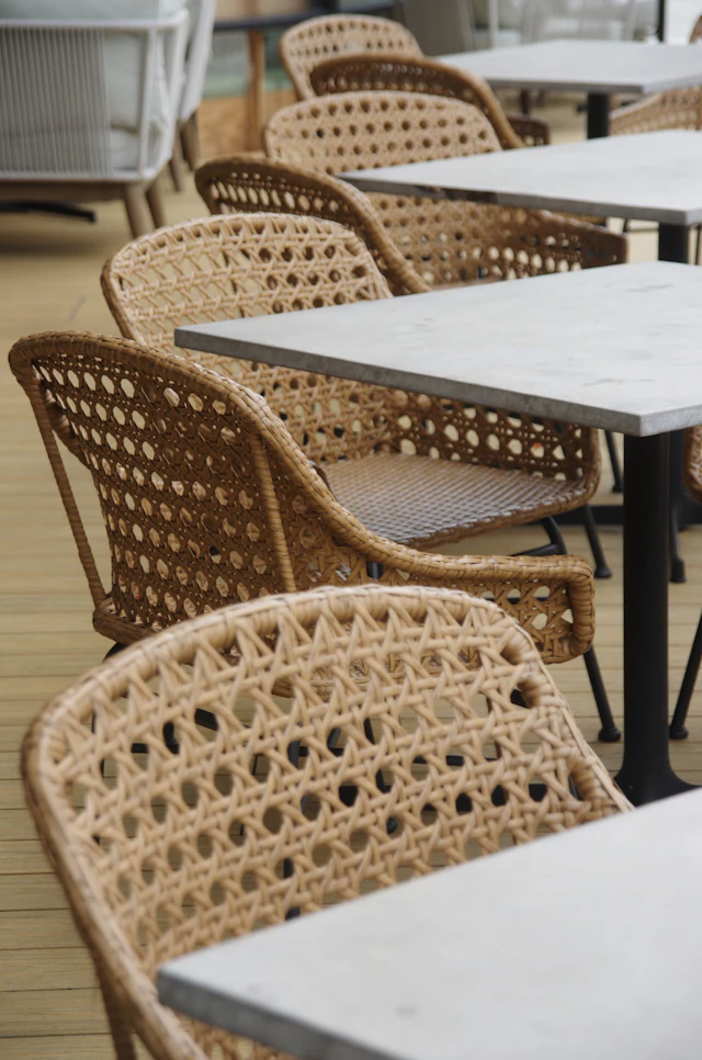 Woven rattan chairs and square tables on a wooden outdoor patio