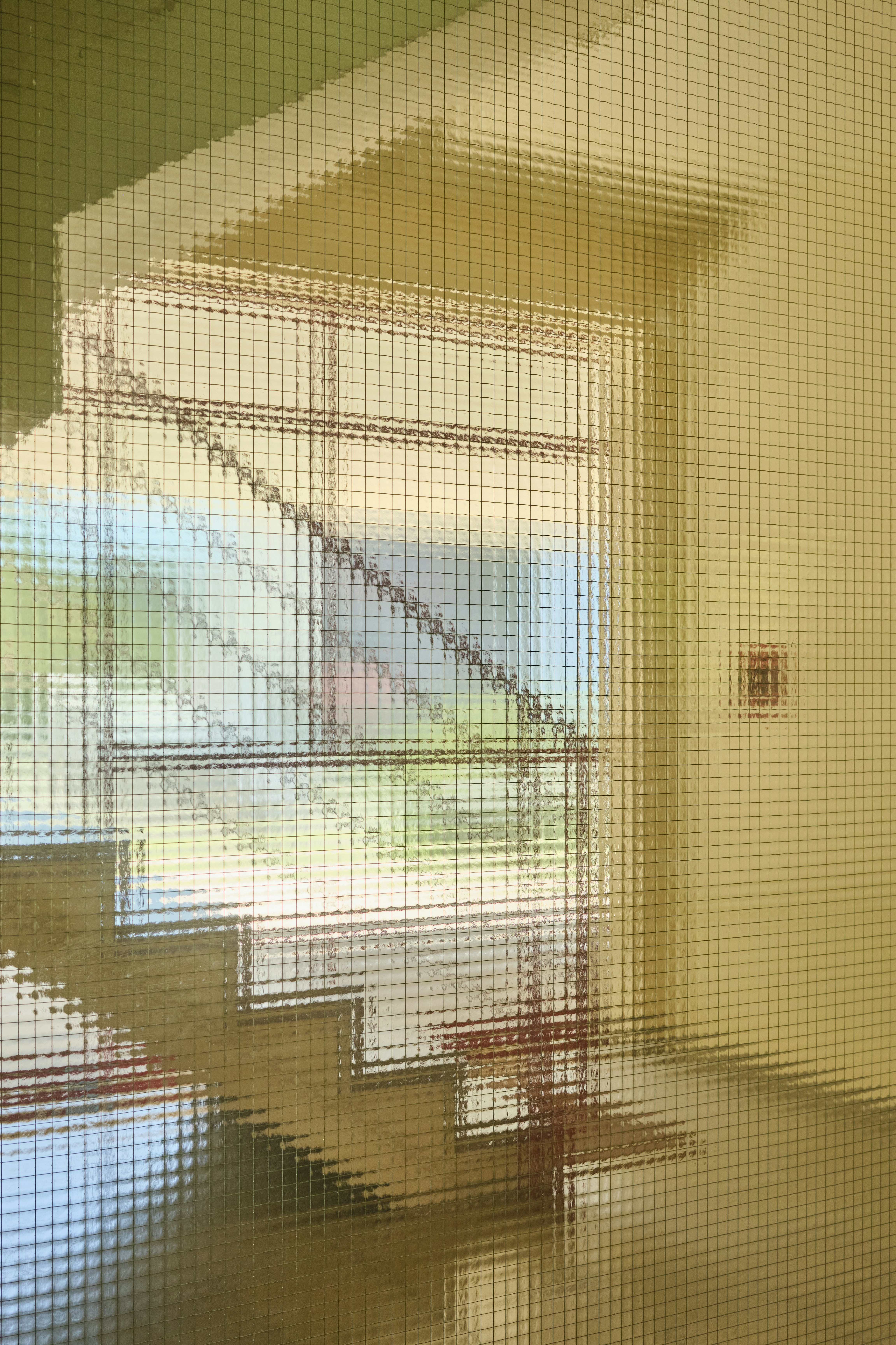 Eine Treppe, die sich in einem strukturierten Glasfenster mit einem Rastermuster spiegelt