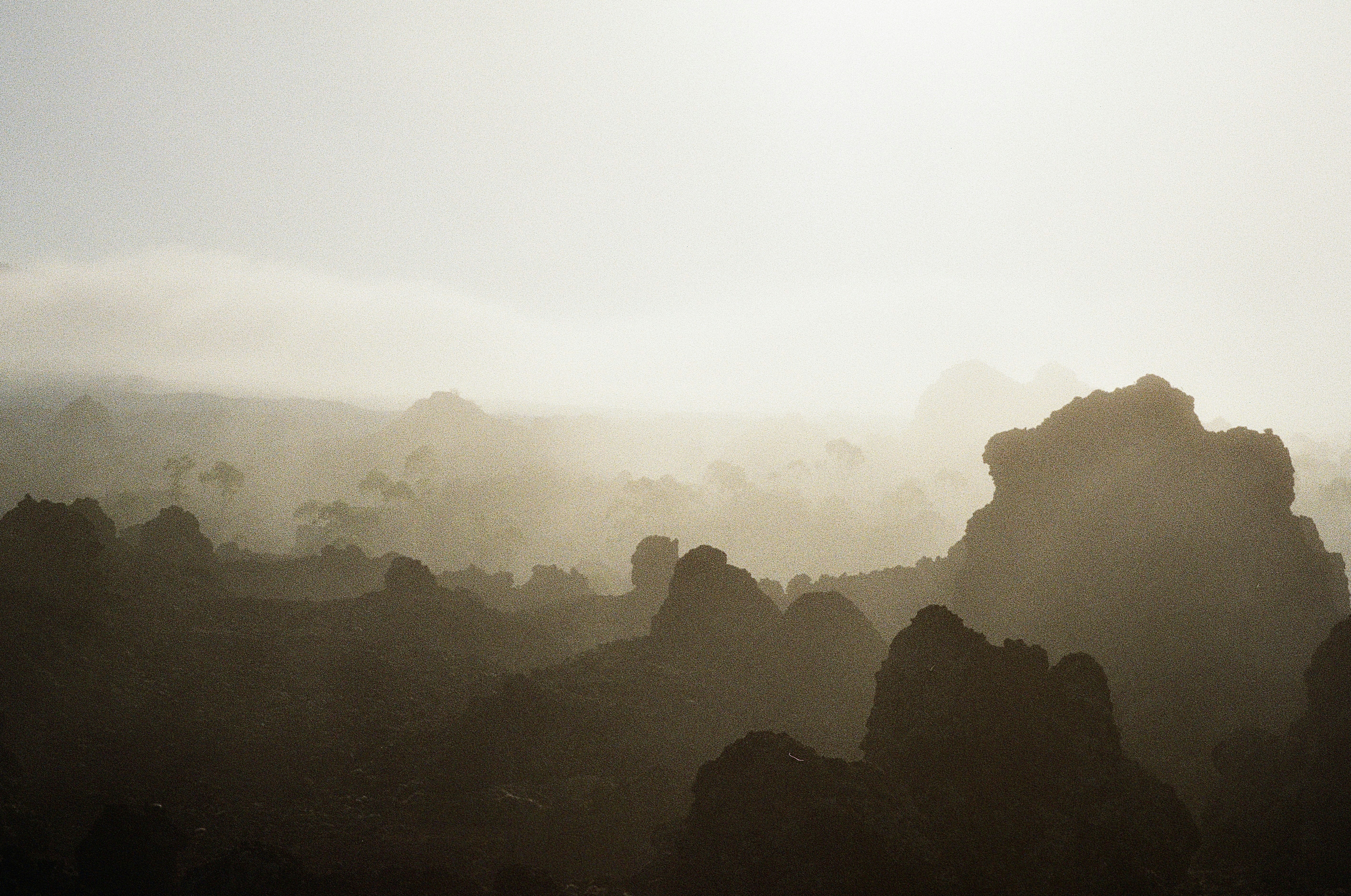 Dark volcanic rock formations in a misty landscape under a pale sky