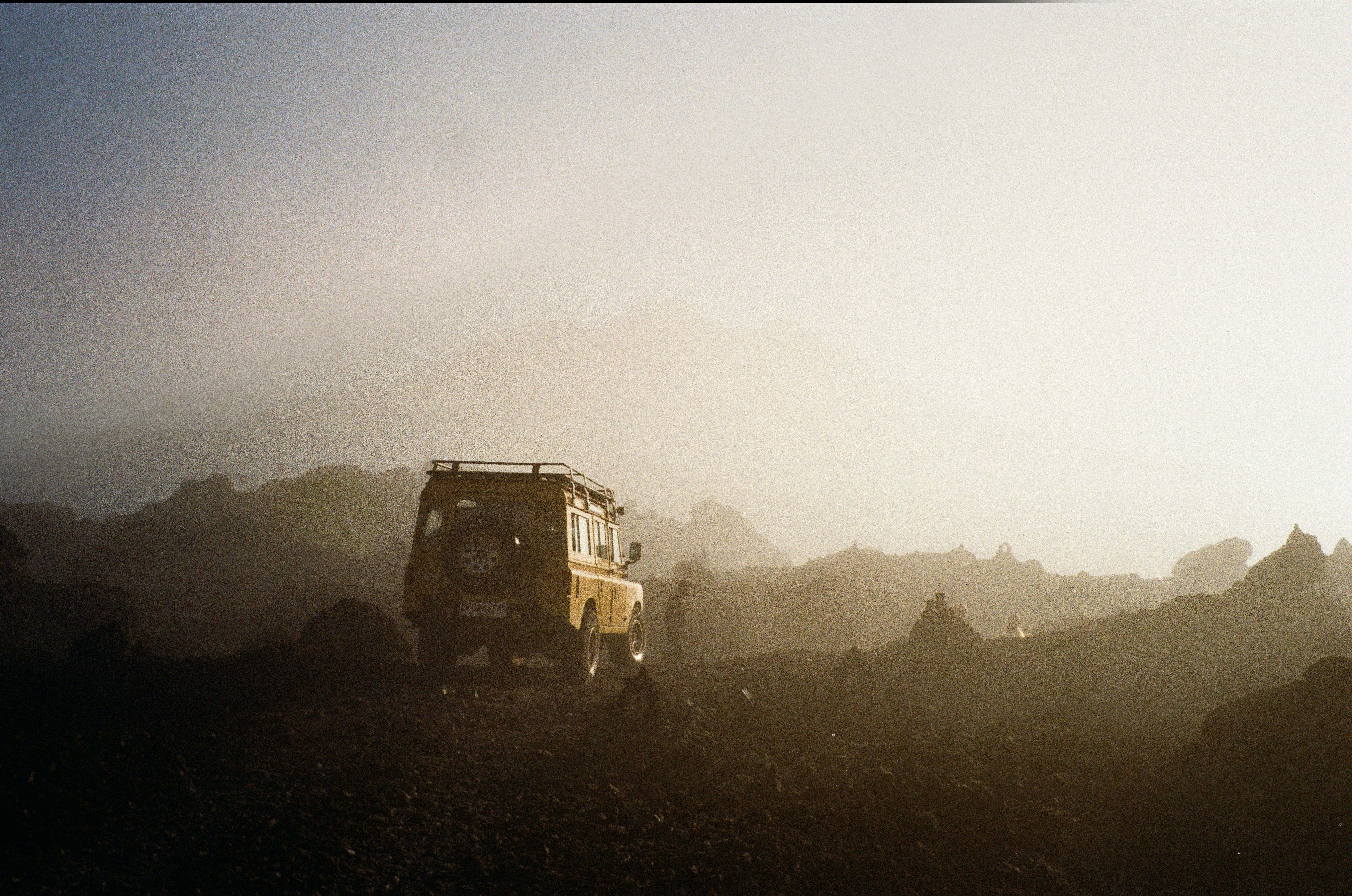 A yellow off-road vehicle on a rocky volcanic landscape in thick fog