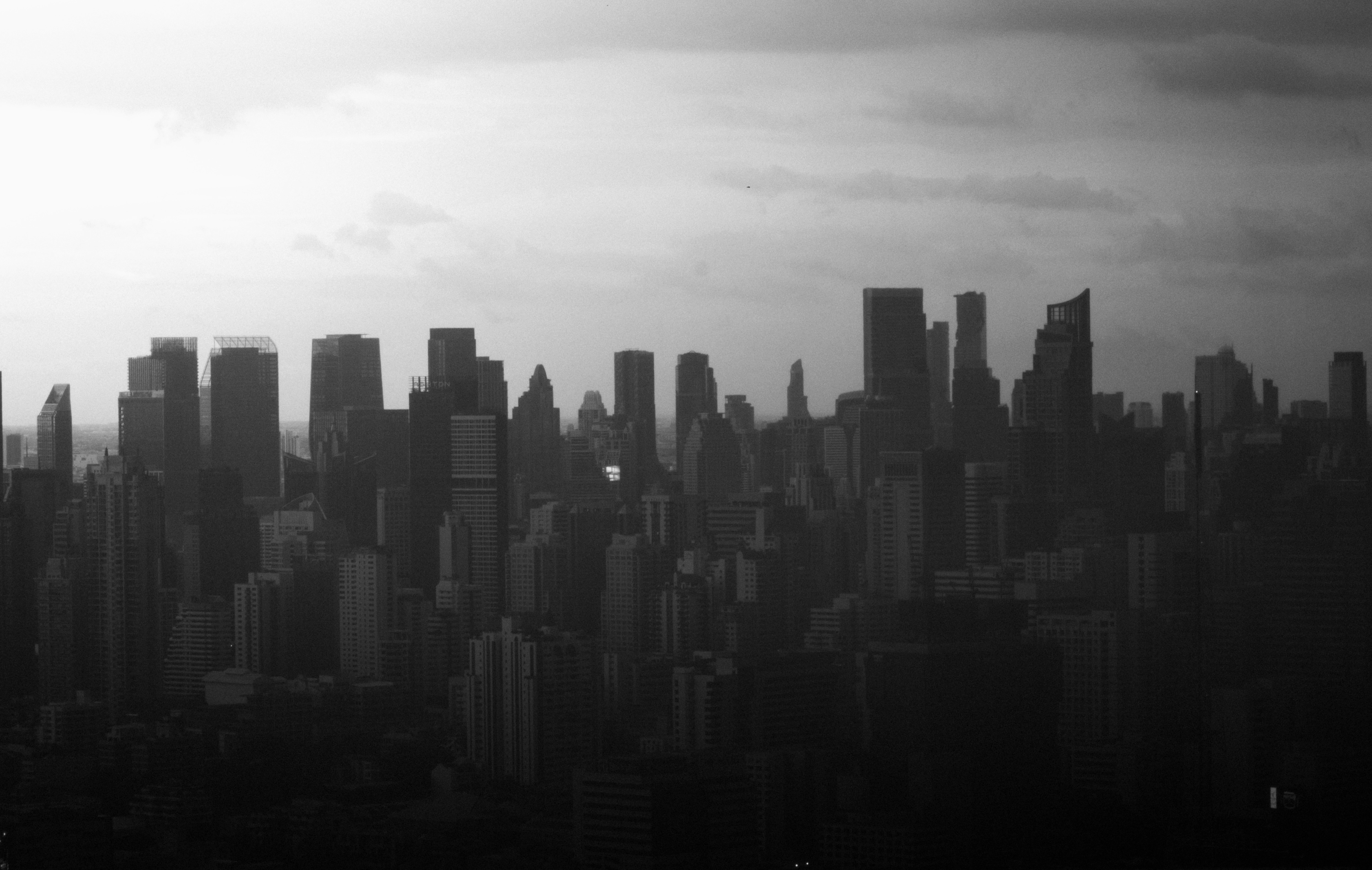 Pemandangan kota hitam putih dengan gedung pencakar langit yang padat di bawah langit berawan