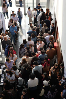 A large group of people standing in a long queue inside a building