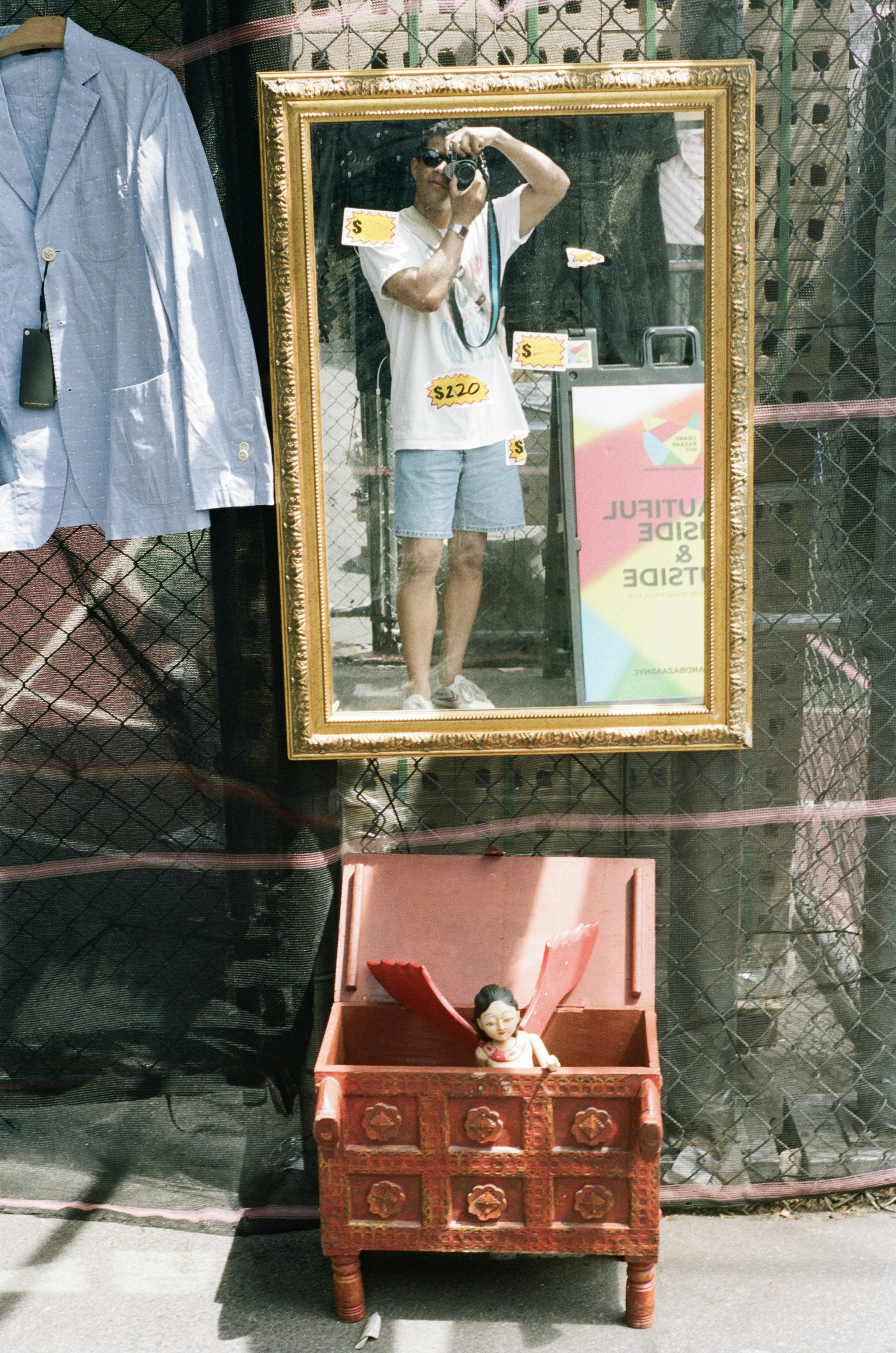 A person taking a mirror selfie with a camera beside a red wooden chest