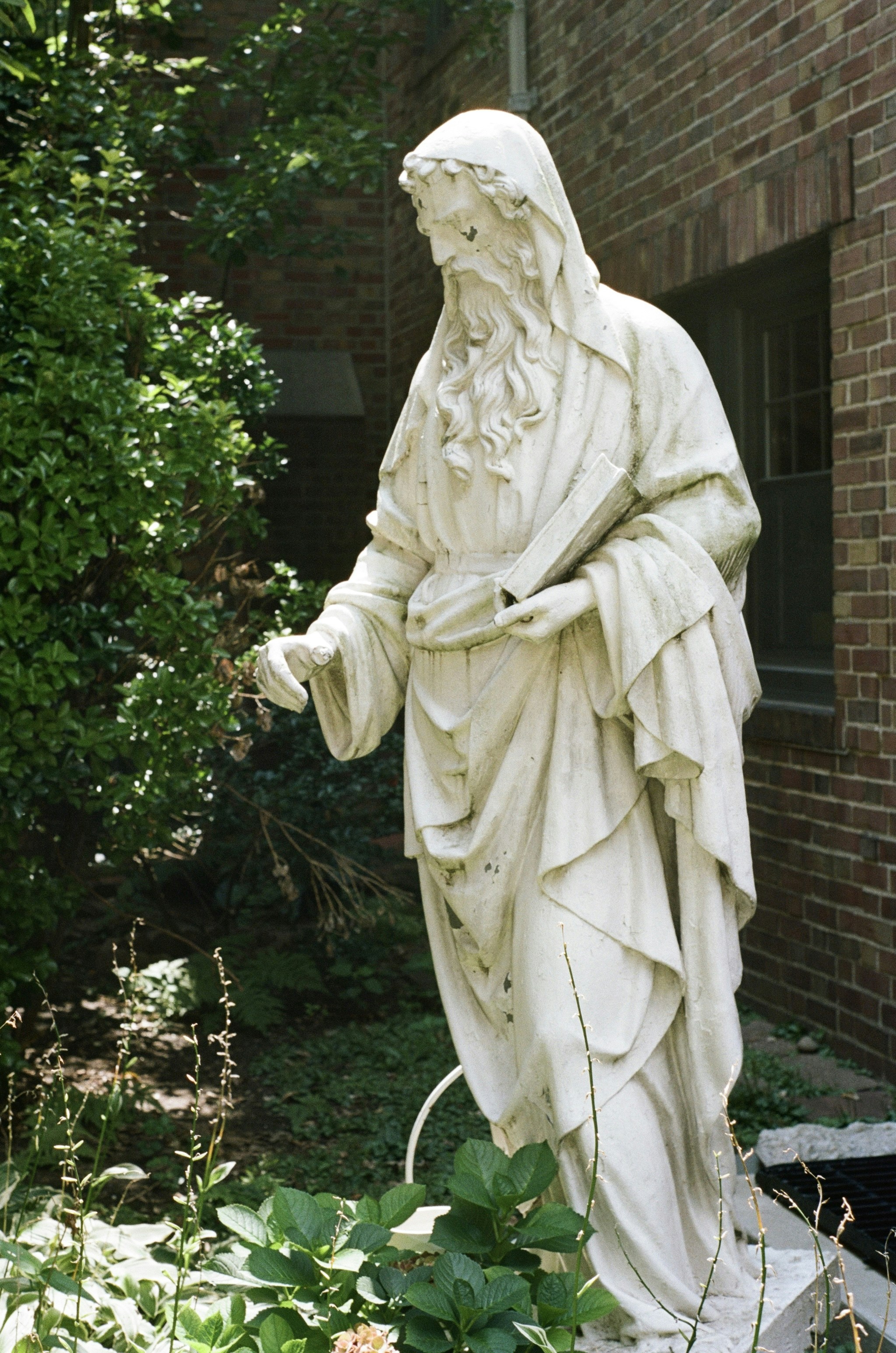 A white stone statue of a bearded man in robes holding a book