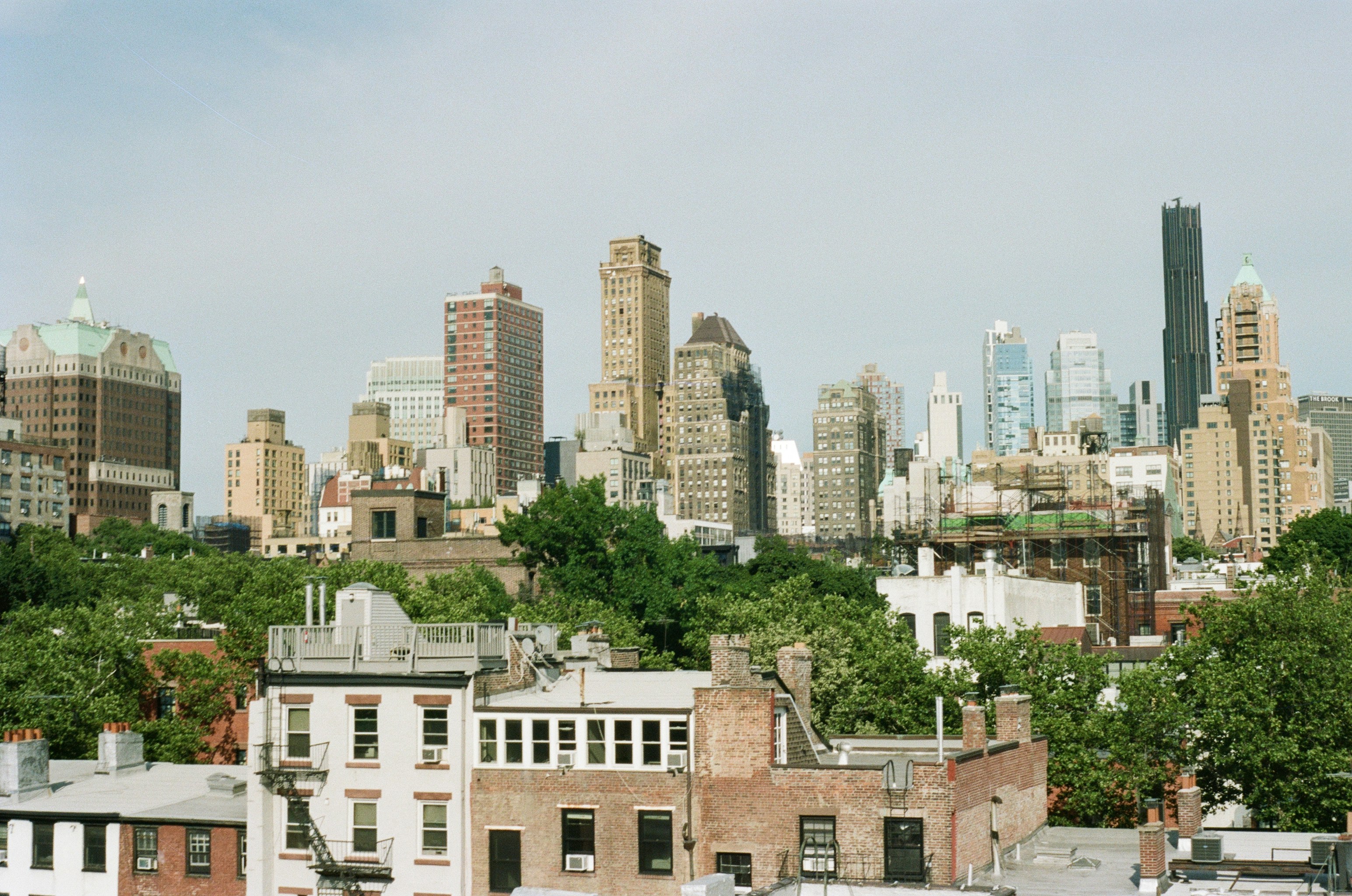 Low-rise brick buildings in the foreground with a dense city skyline behind