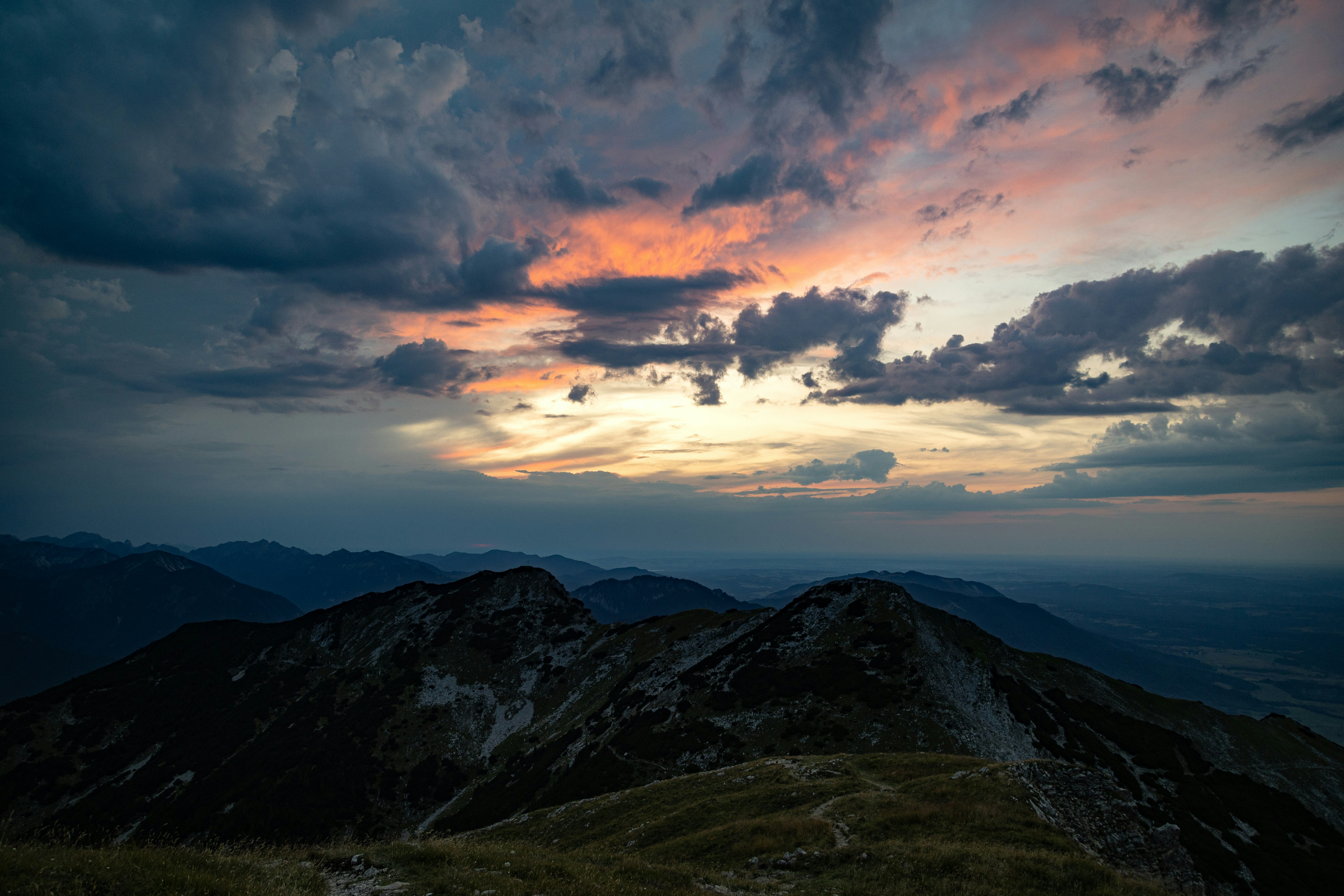 Dark mountain peaks under a sky with orange clouds and long shadows