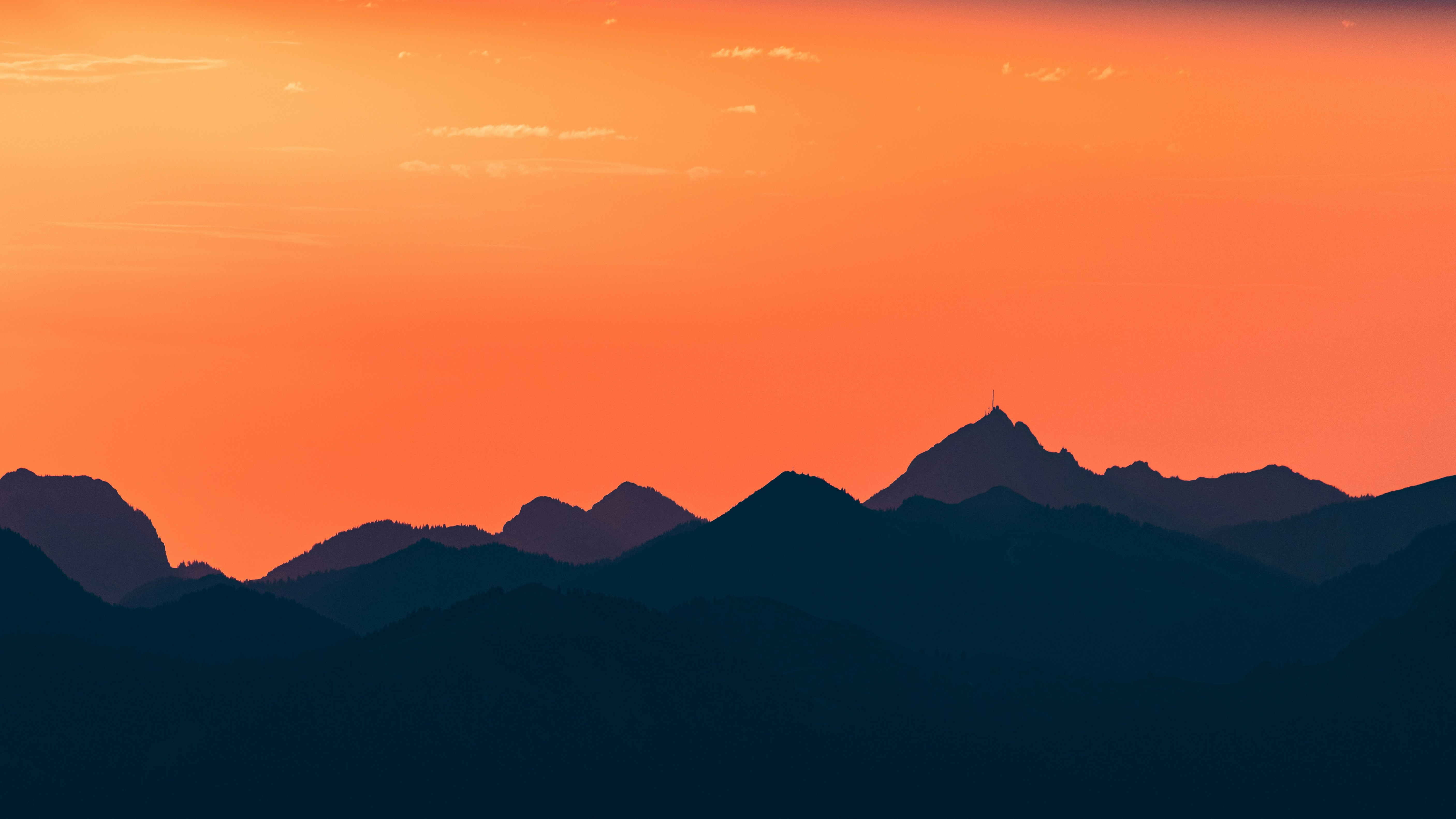 Dark mountain silhouettes against a vibrant orange sky
