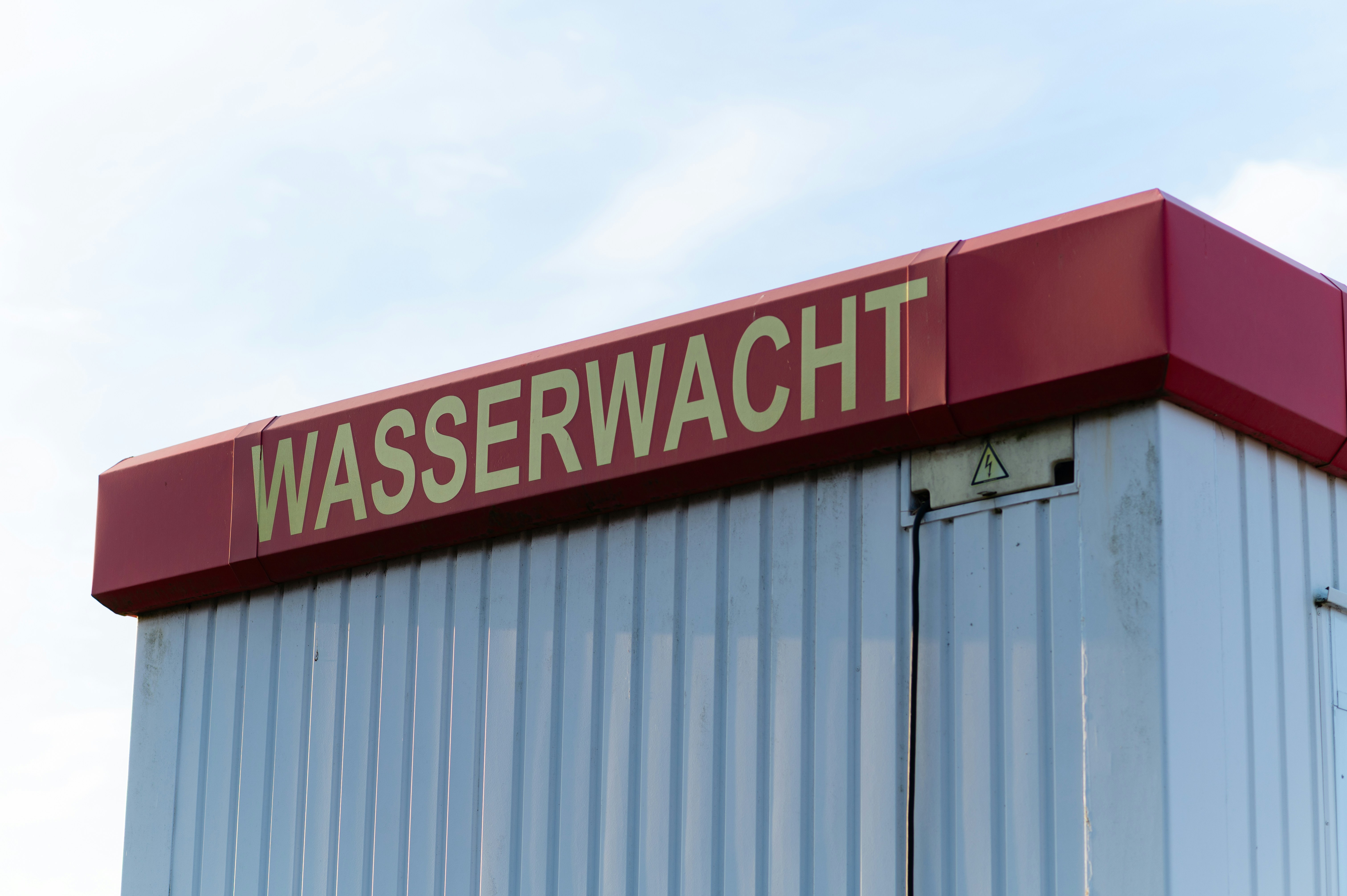 A white corrugated metal structure with a red sign reading WASSERWACHT