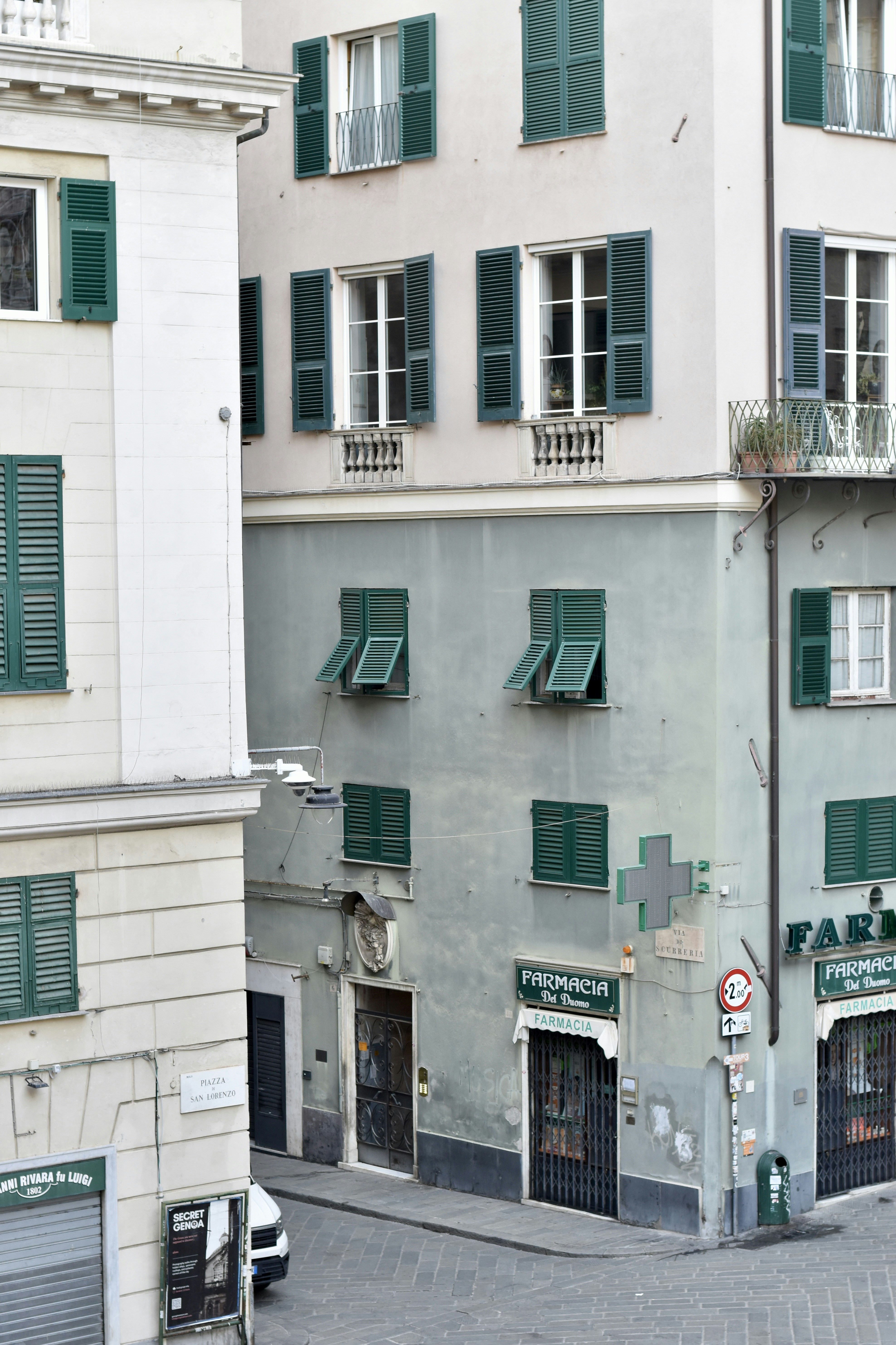 A pharmacy with green shutters on a street corner in Genoa, Italy