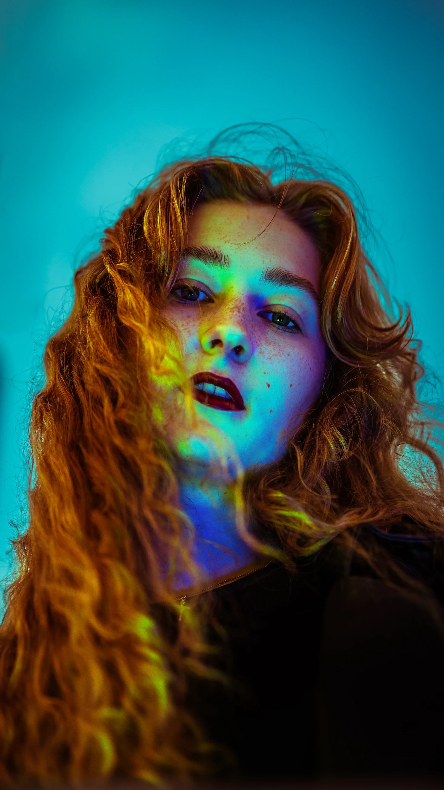 Long curled hair lit by a hard blue key and a yellow kicker