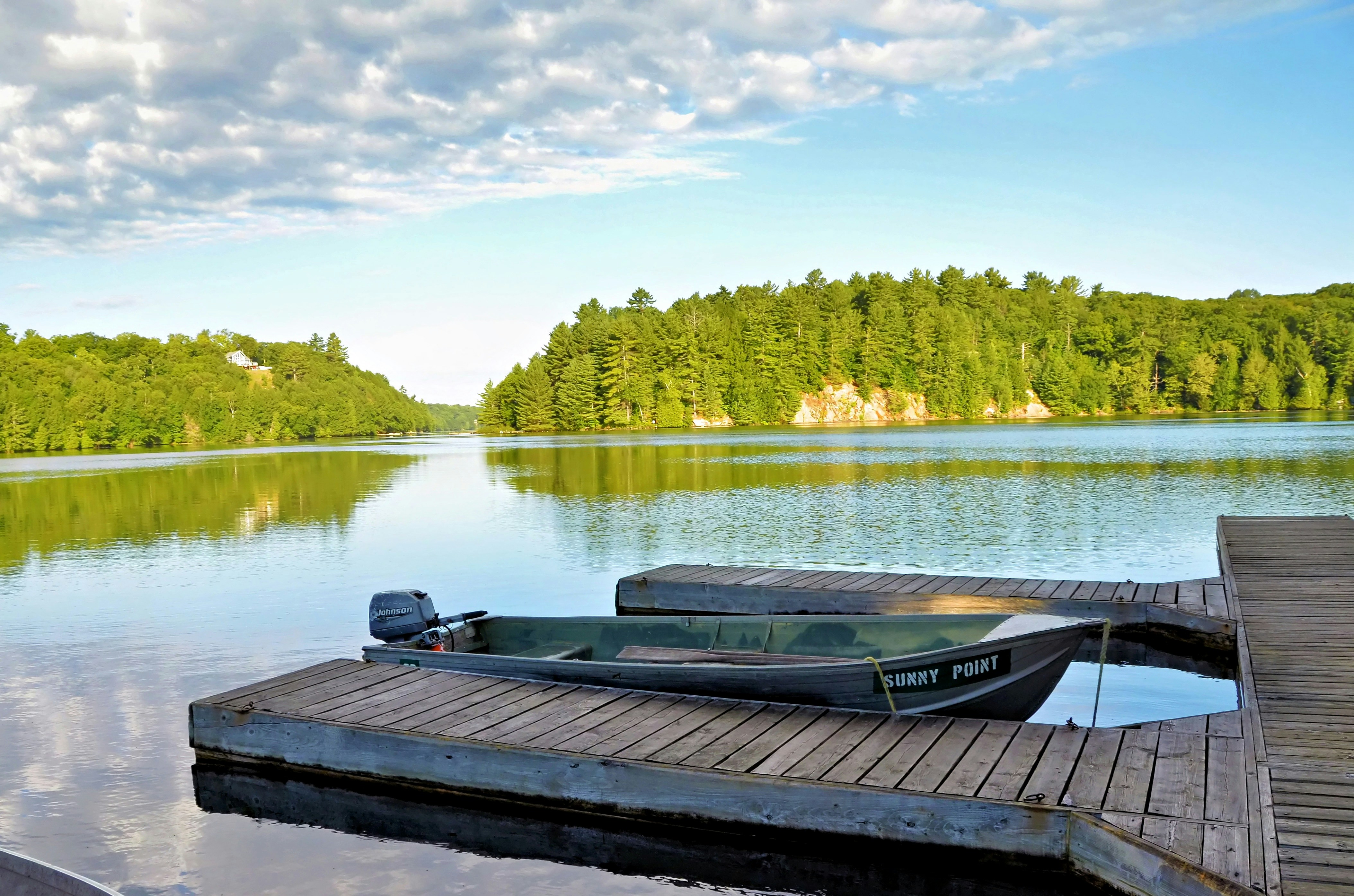 A small motorboat named Sunny Point moored at a wooden dock on a lake