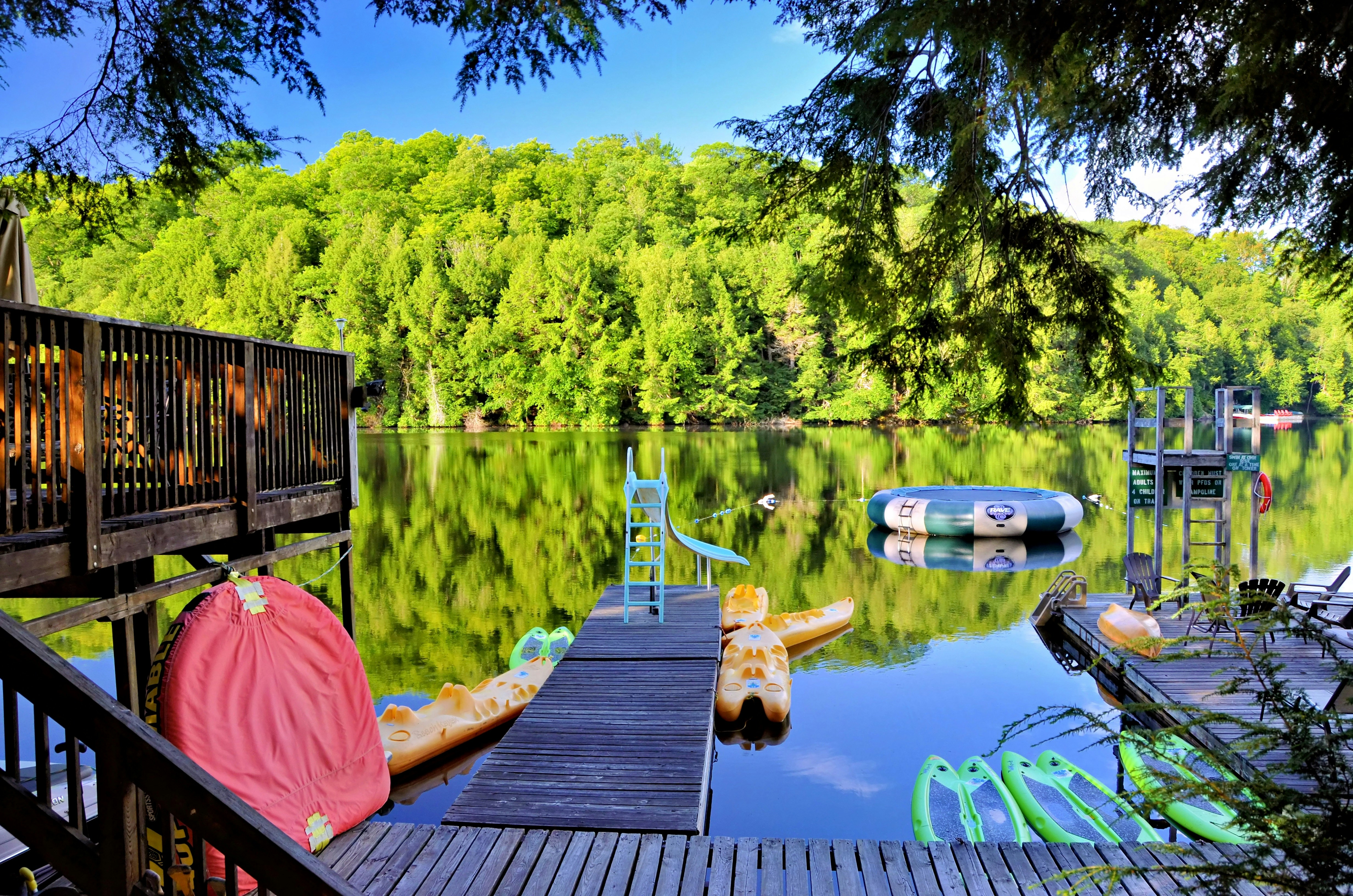 A wooden dock with yellow kayaks and a slide on a calm lake