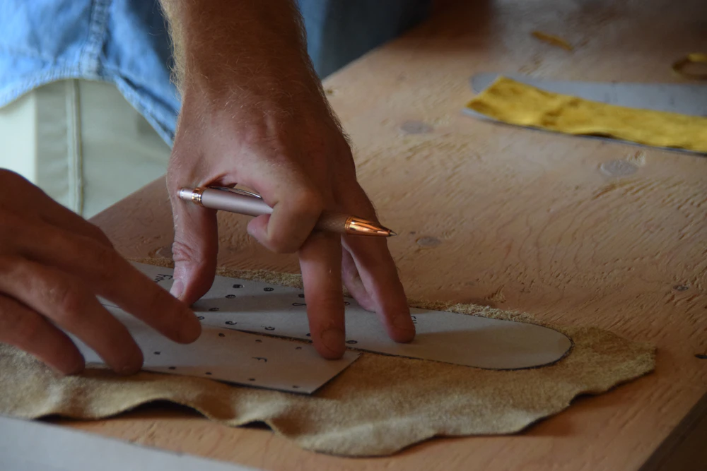 Artisan traçant un patron sur une peau de cuir