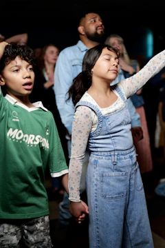 A boy and a girl holding hands with eyes closed in a crowd