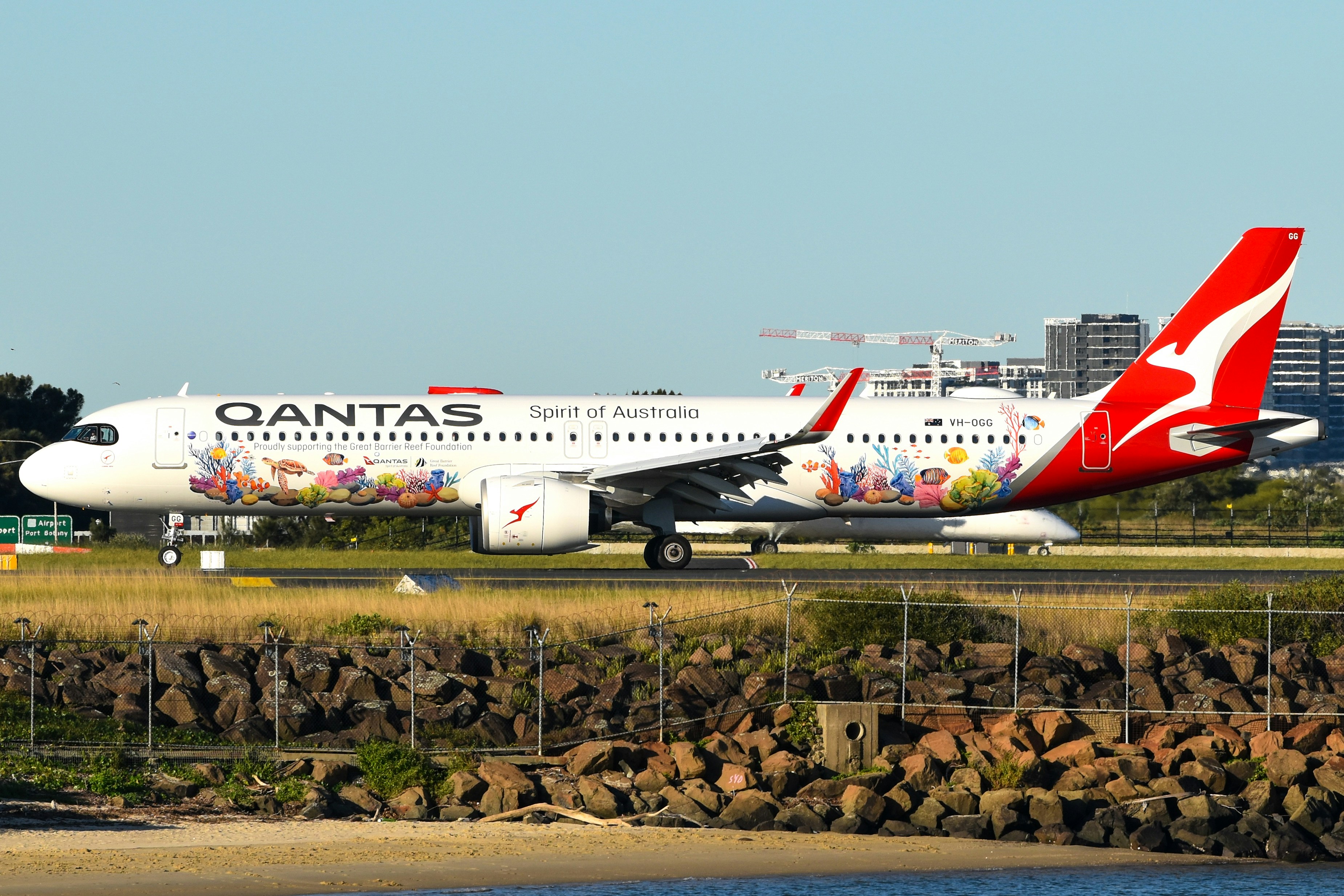 A Qantas passenger jet with a colorful coral reef livery taxiing on a runway