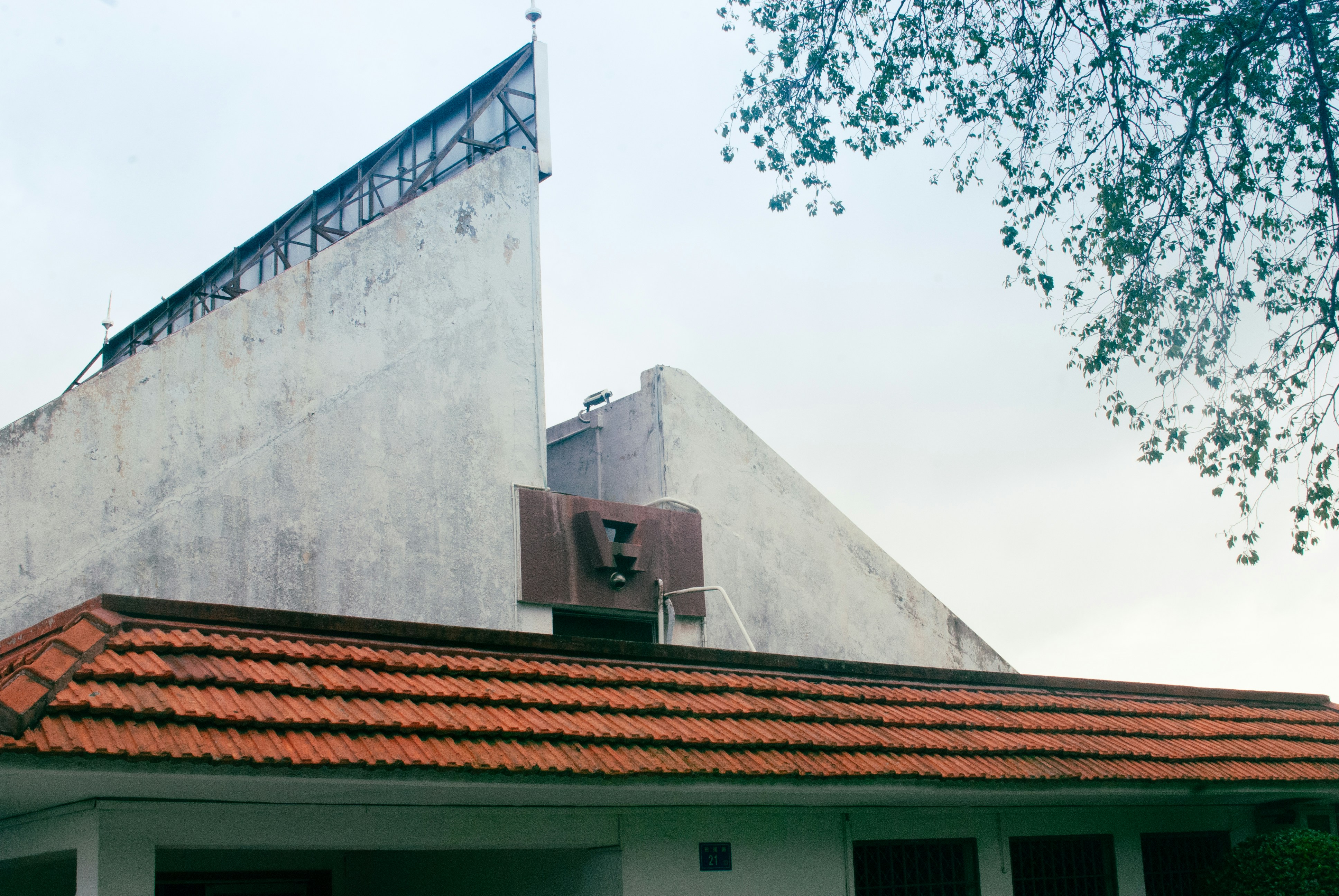 A building with a tall angular concrete facade and a red tiled roof