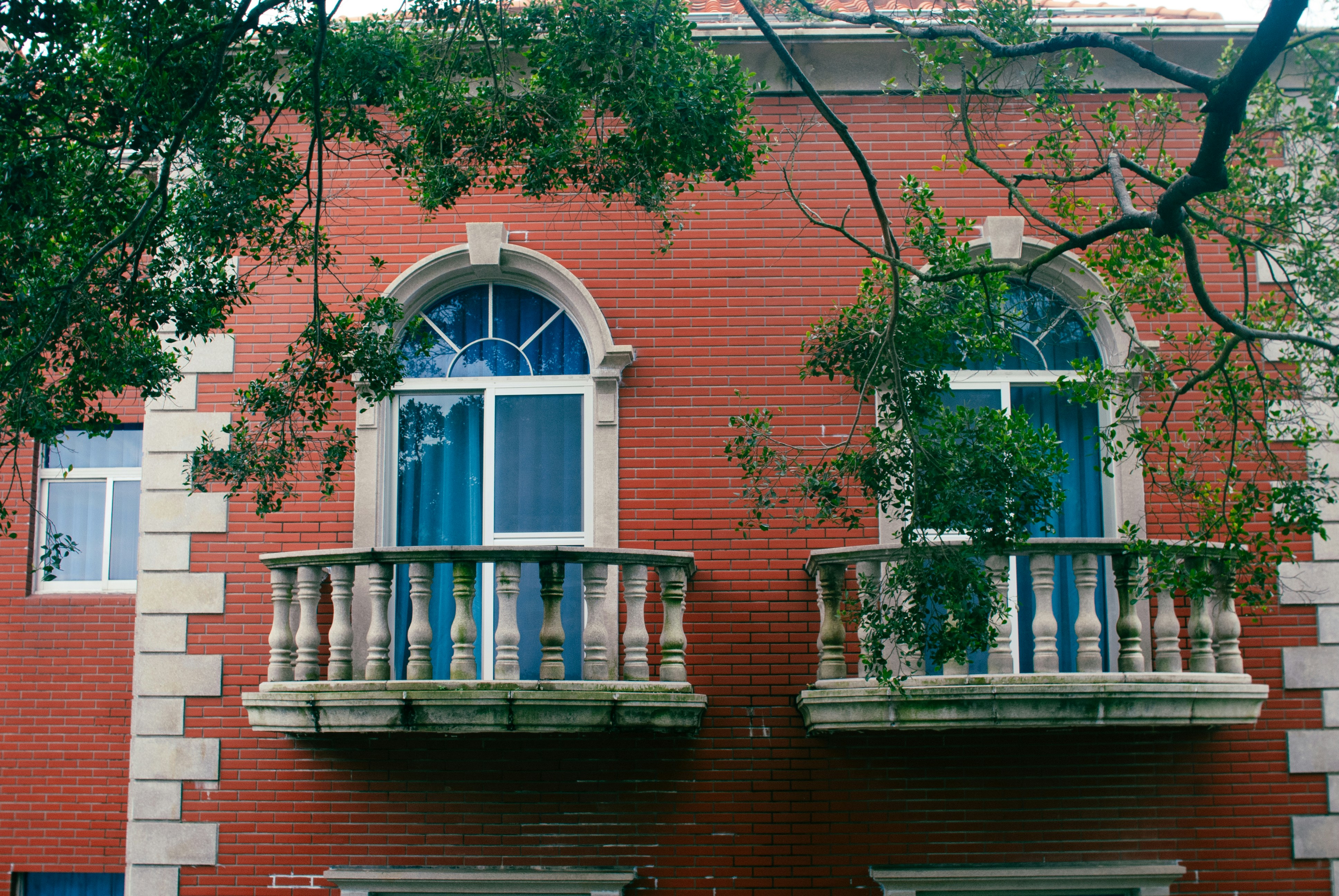 Two arched balconies with stone balustrades on a red brick building facade
