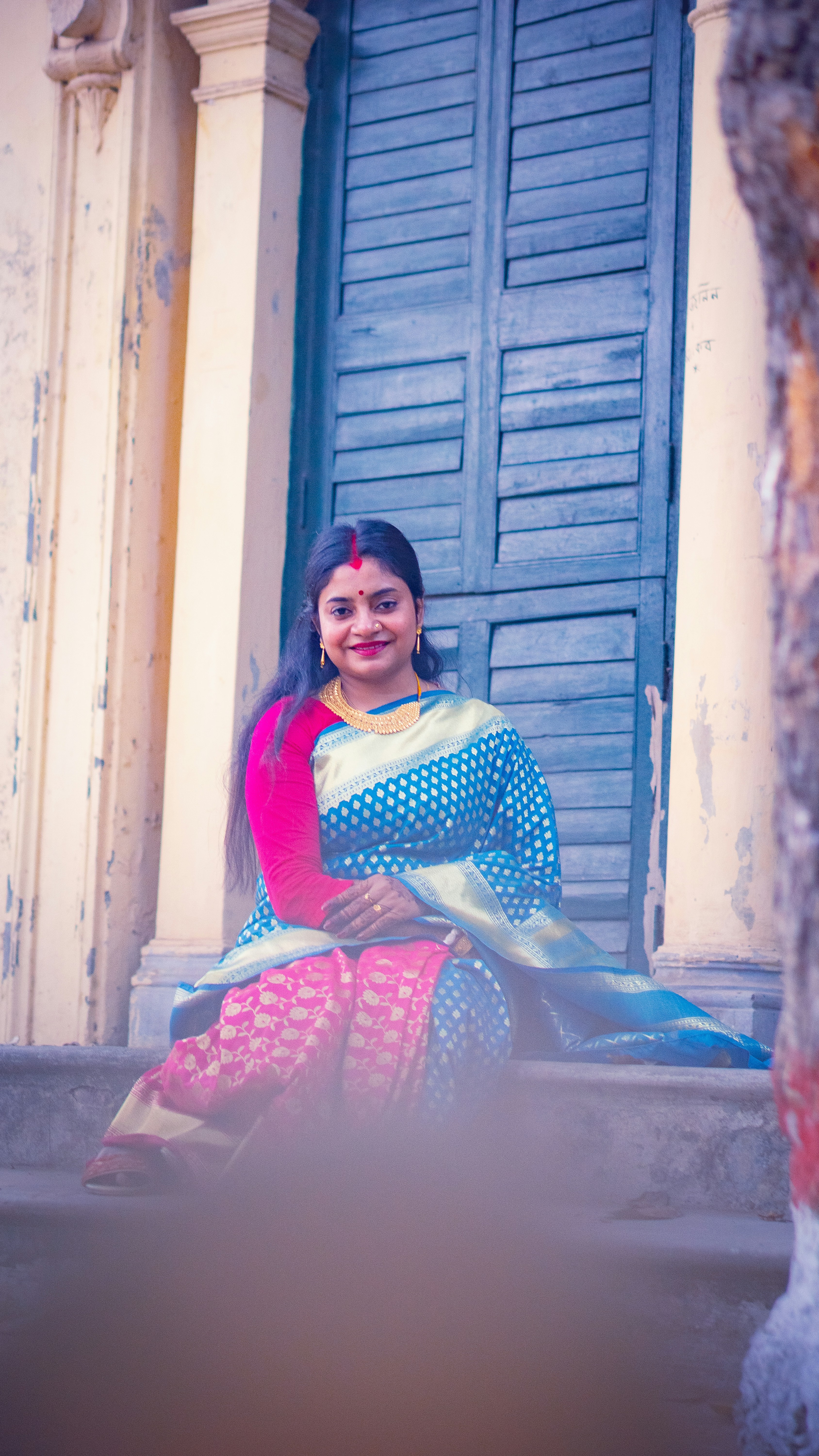 A woman in a blue and pink sari sitting on stone steps